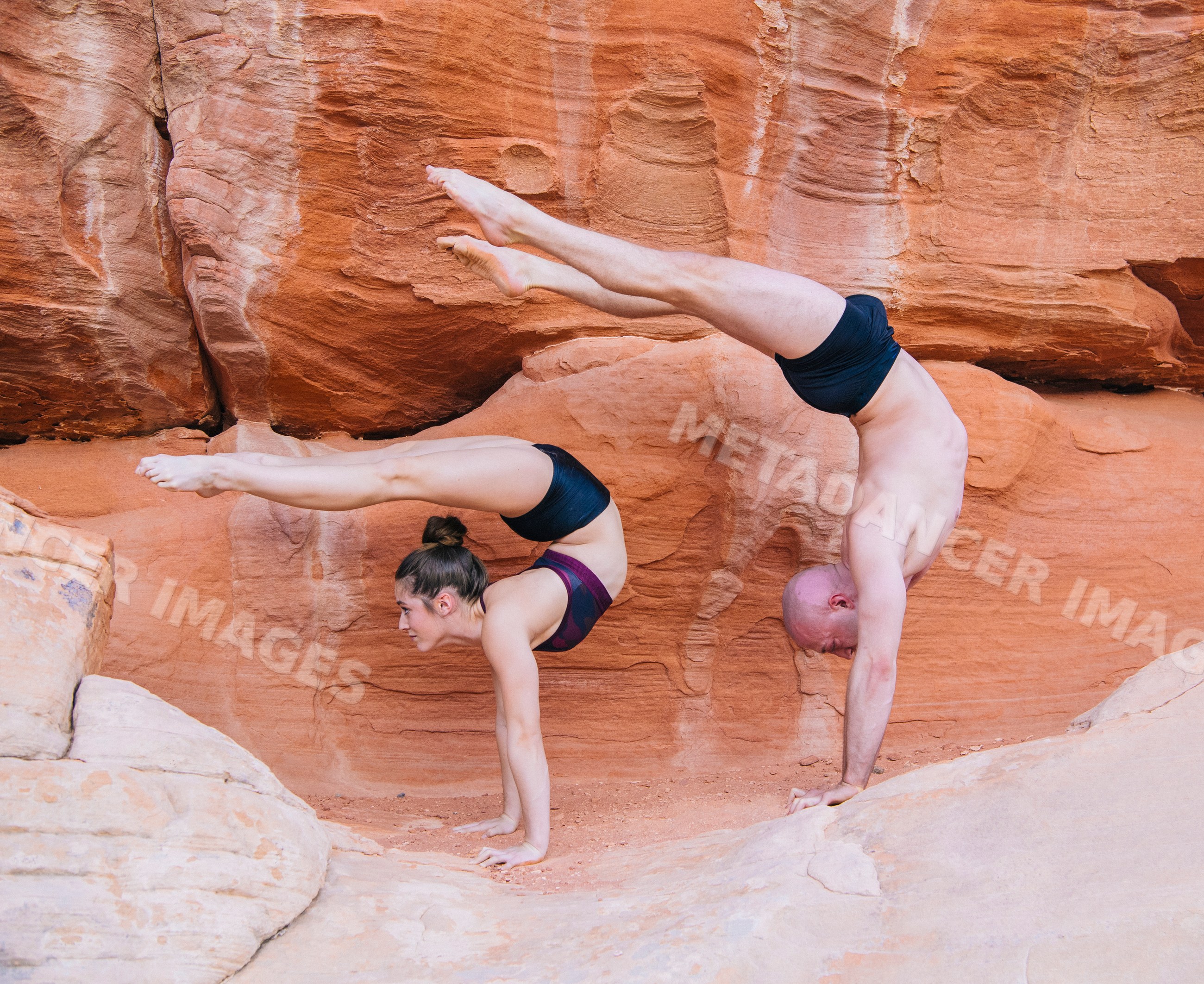 Acrobatic yoga handstands balancing on red rocks outdoors