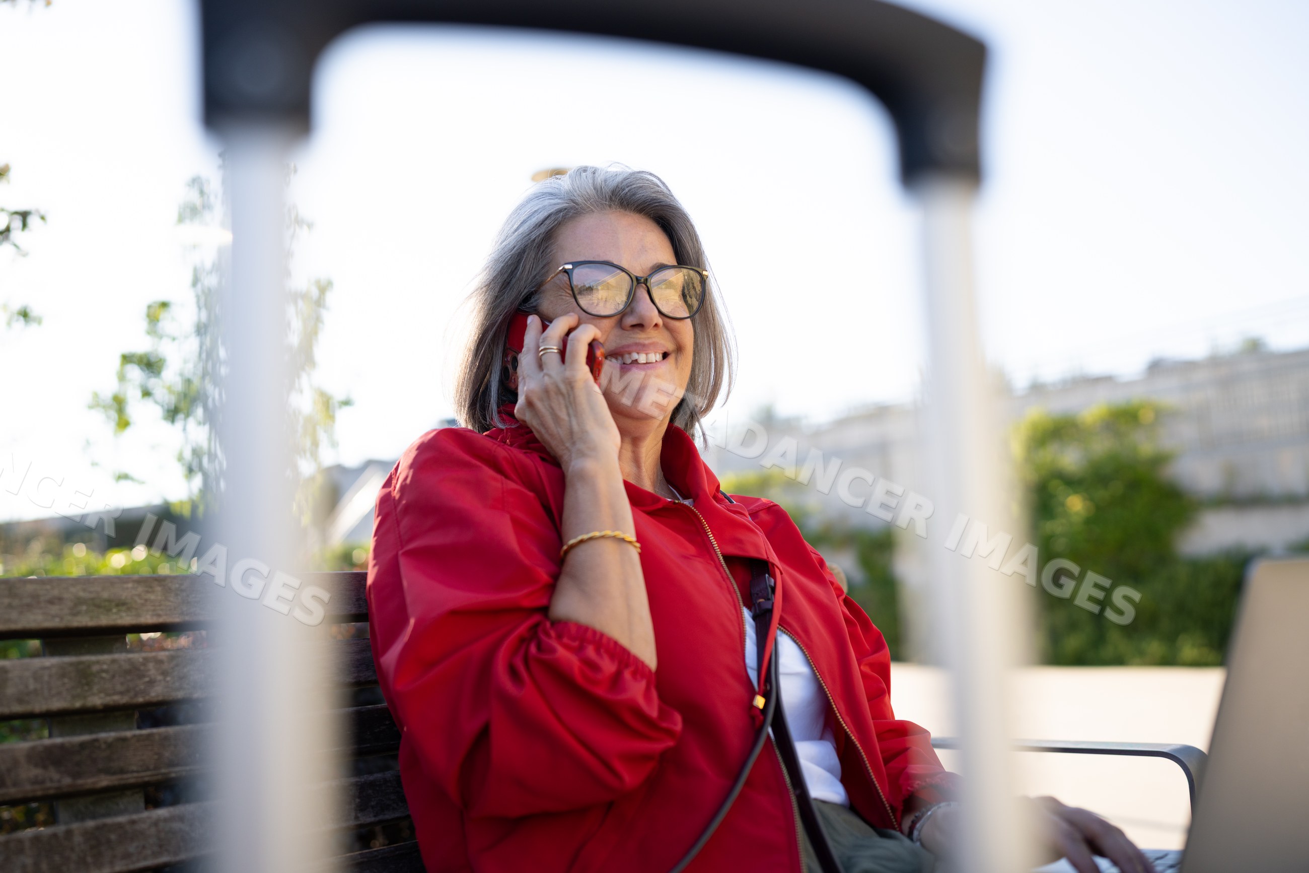 White woman sitting on bench talking on mobile phone outdoors
