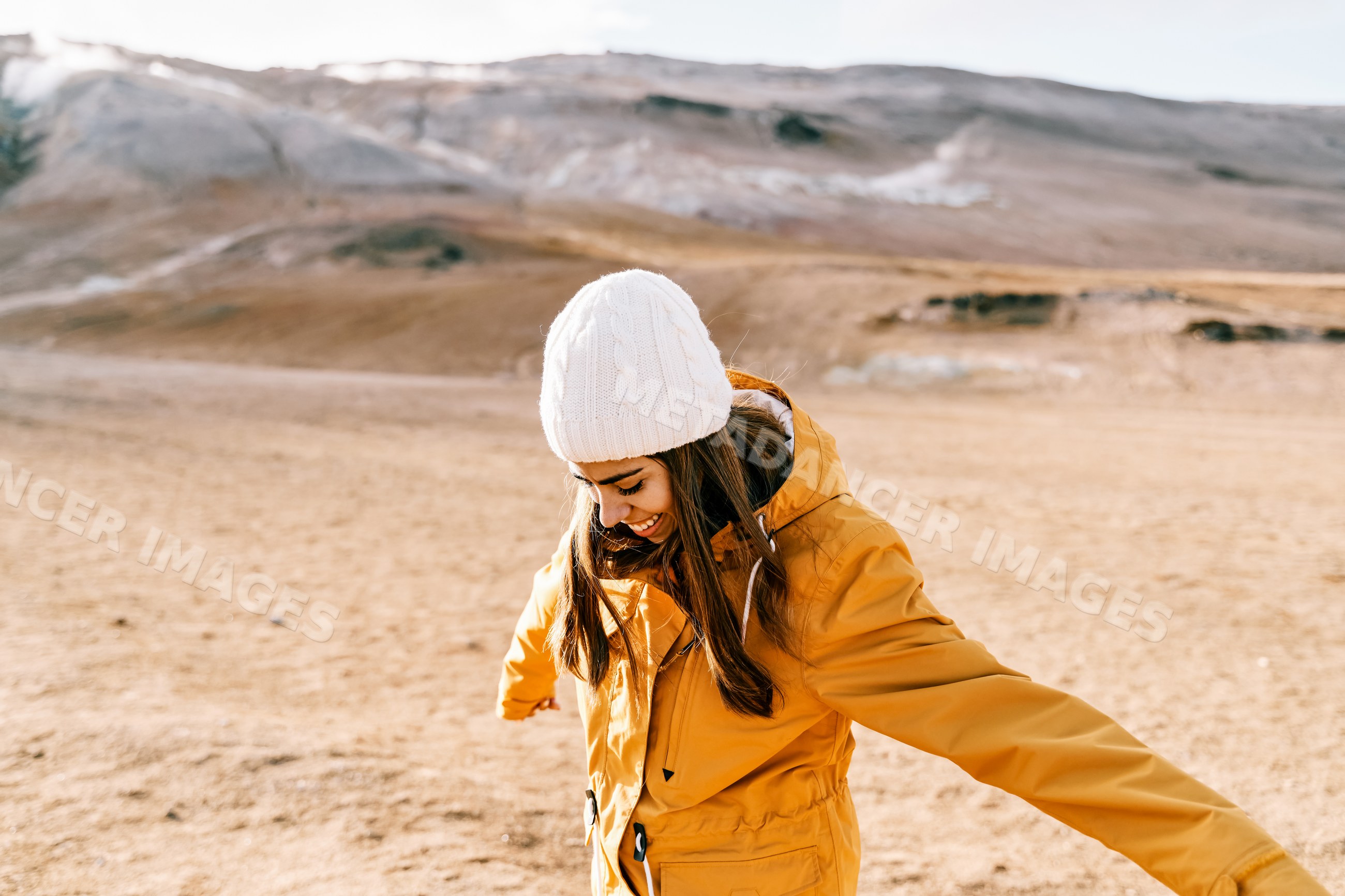 A white woman in a yellow jacket stretches her arms in an Iceland