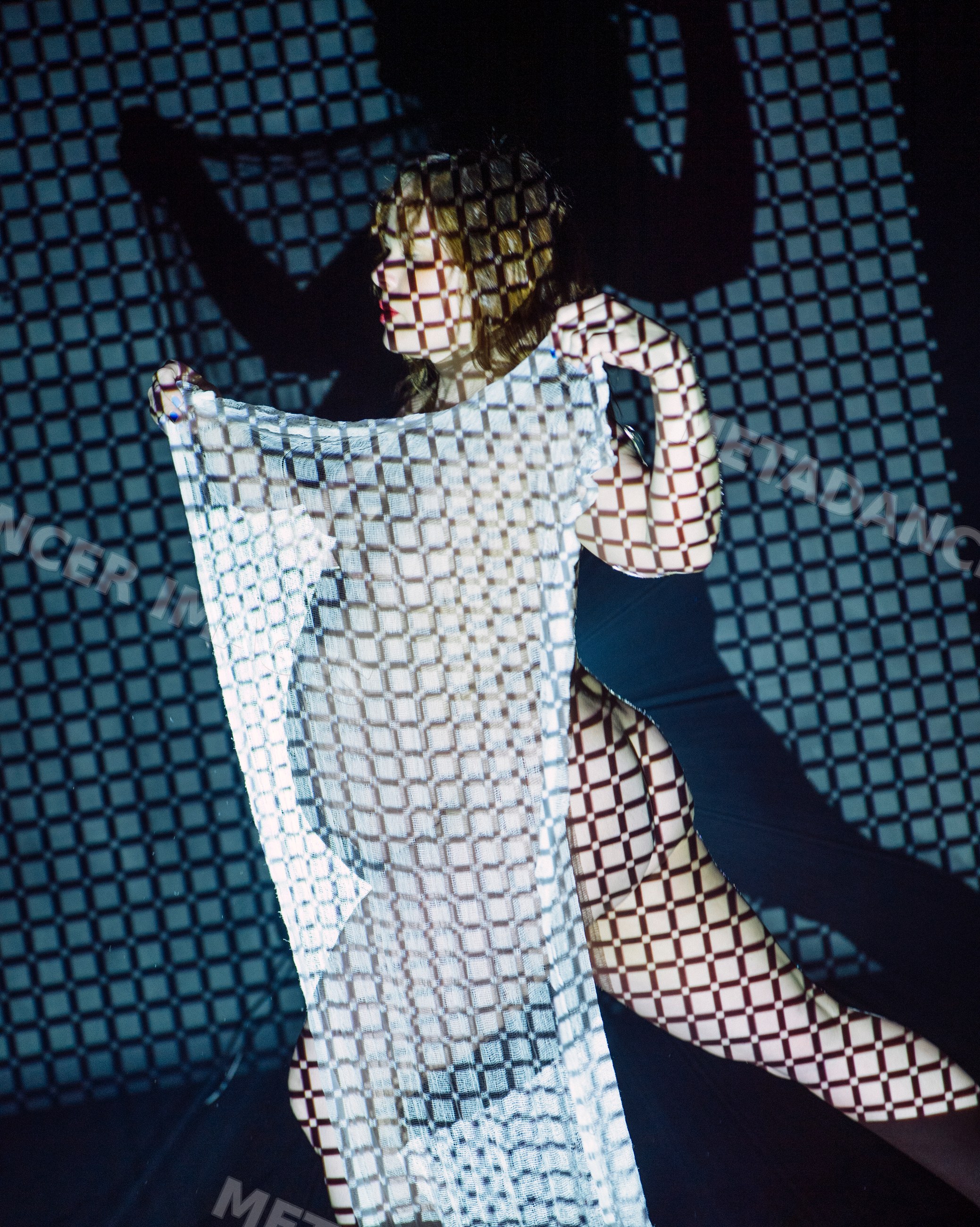 Woman holding white fabric with checkered light projection and shadow
