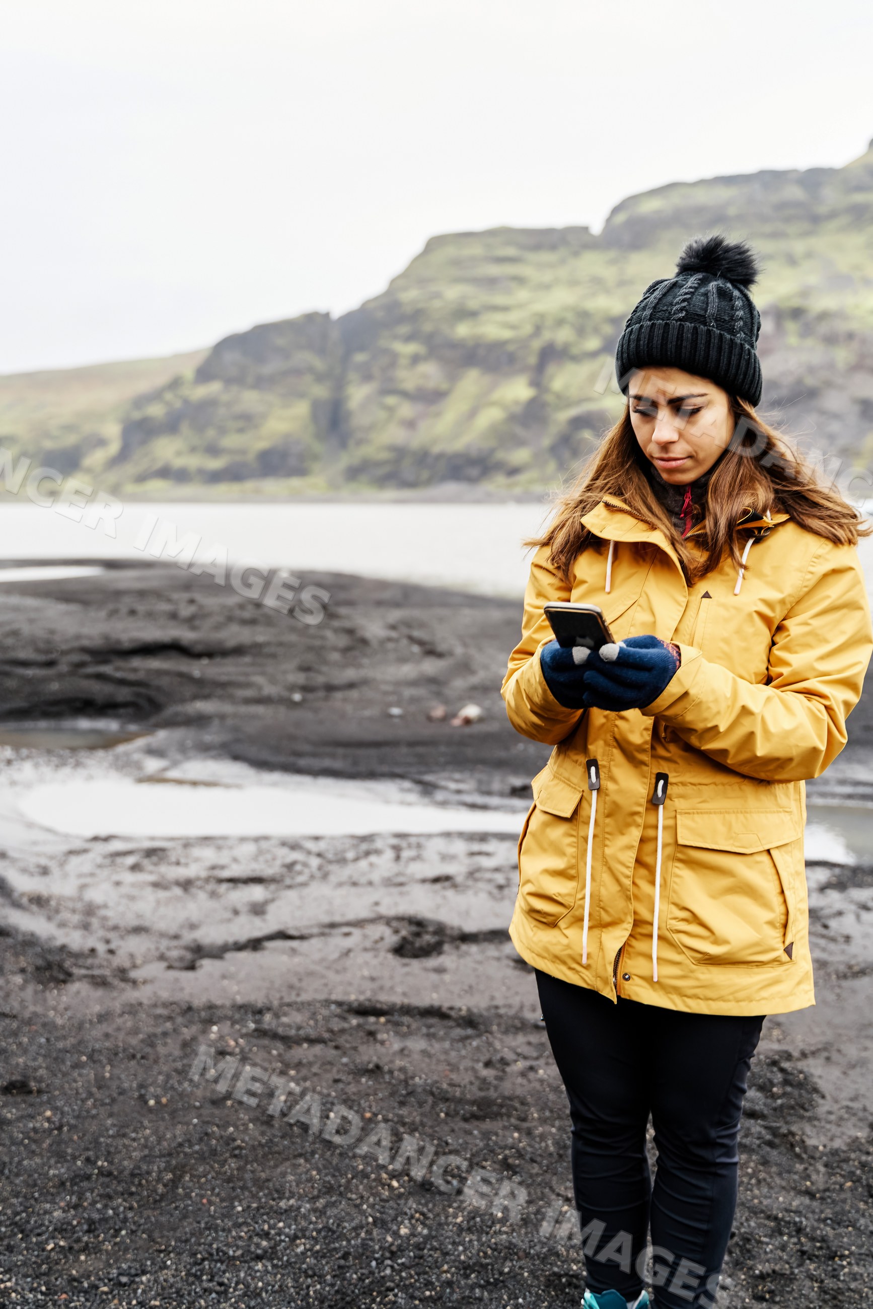 A white woman using her smartphone outdoors on rocky terrain
