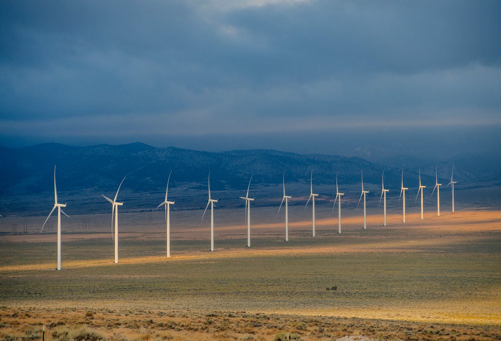 Wind turbines at a wind farm on plains with mountainous backdrop