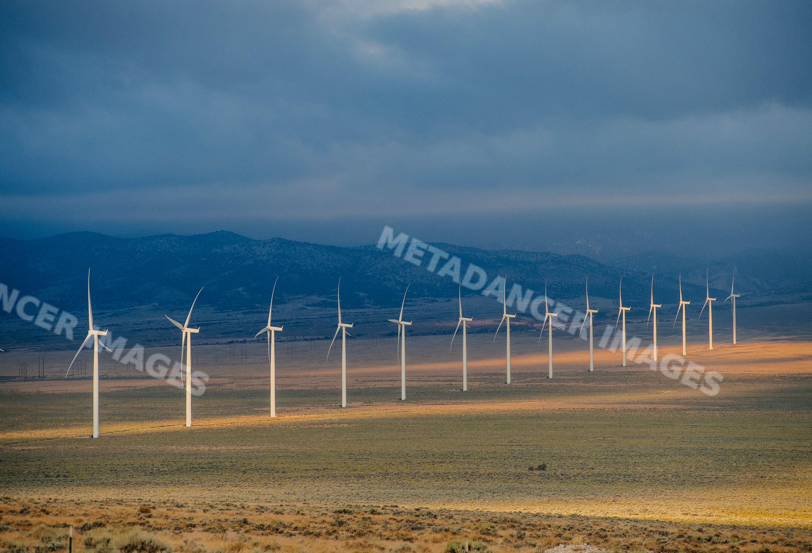 Wind turbines at a wind farm on plains with mountainous backdrop