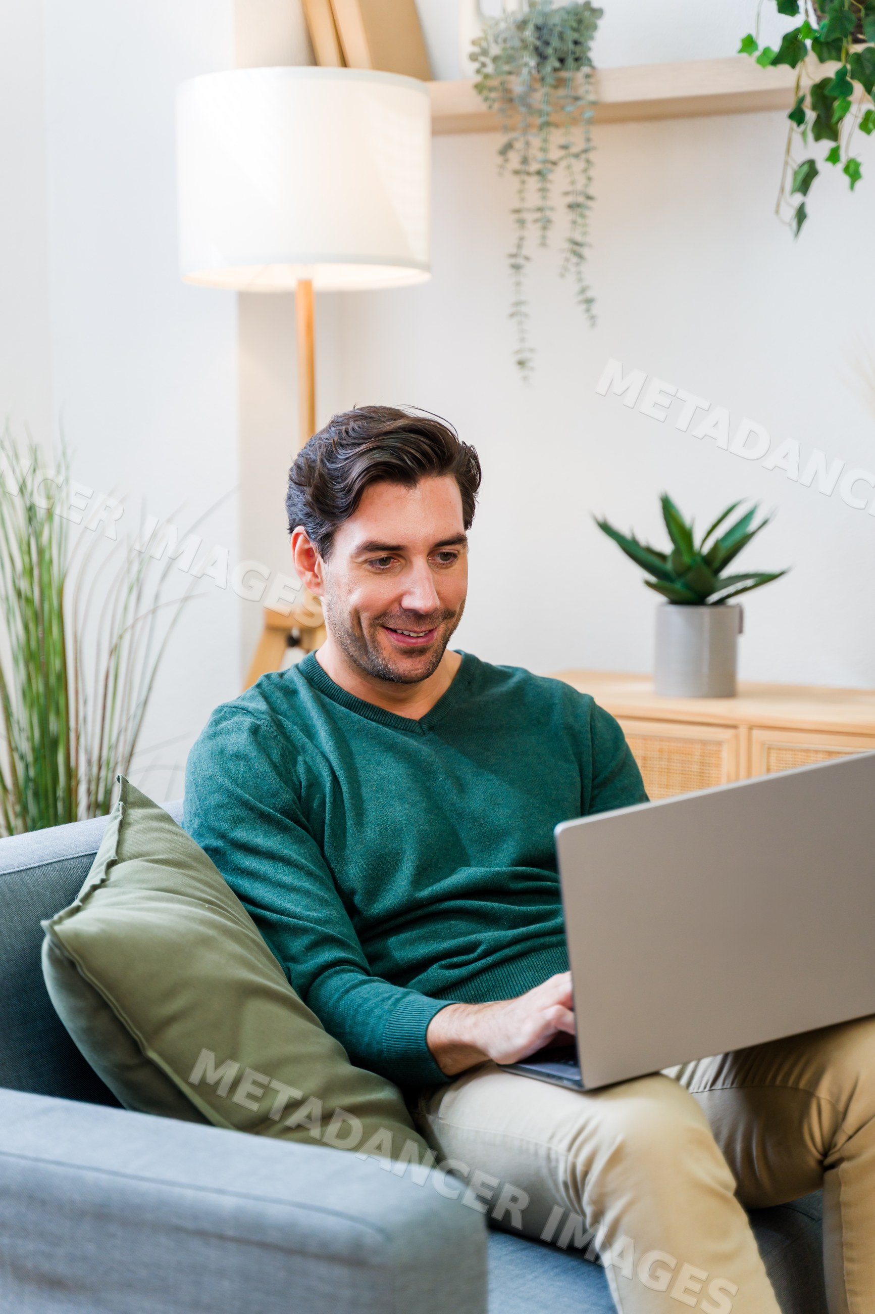White man using laptop on sofa in modern living room