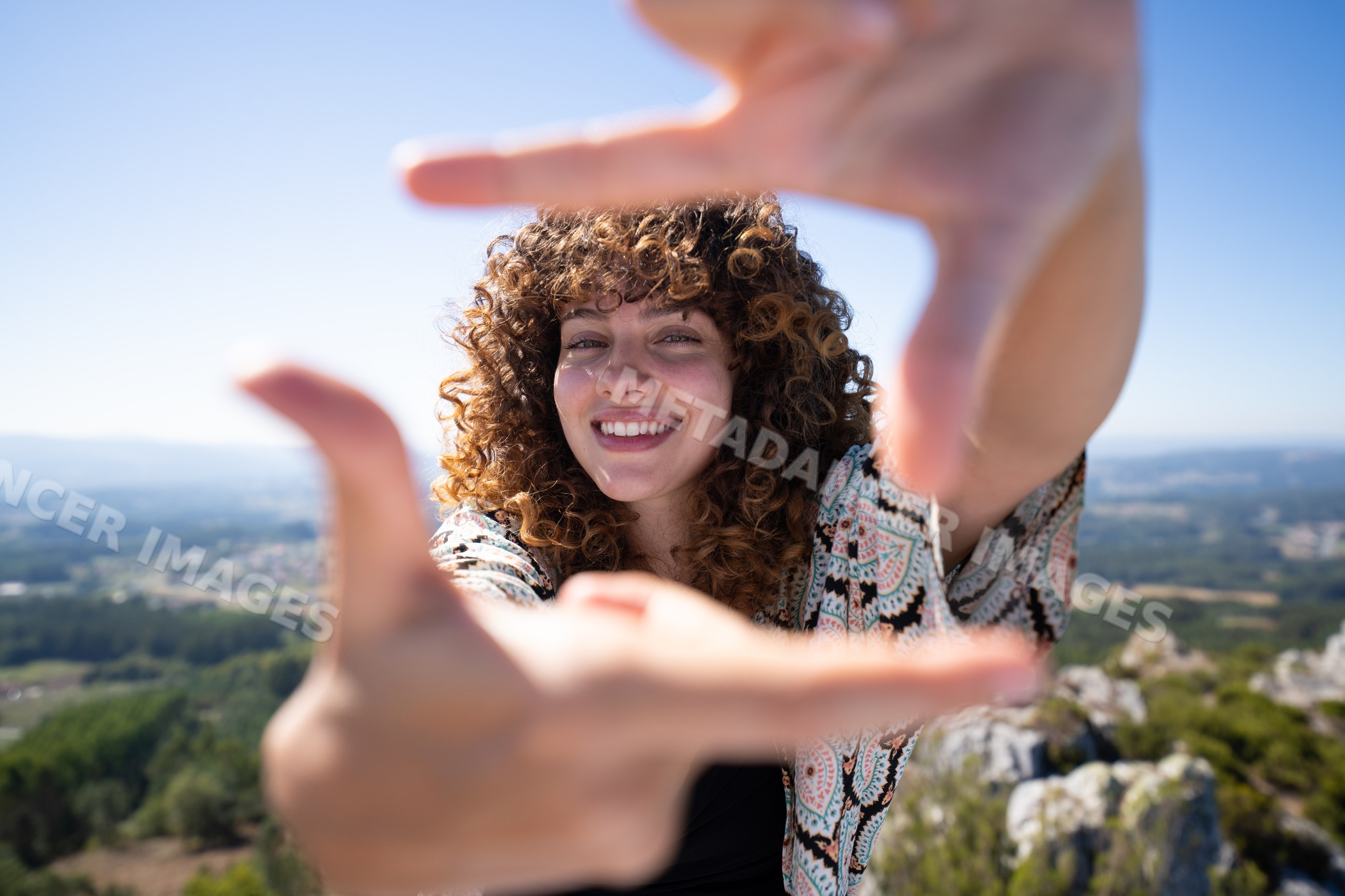 Smiling white woman framing hands with mountain nature background