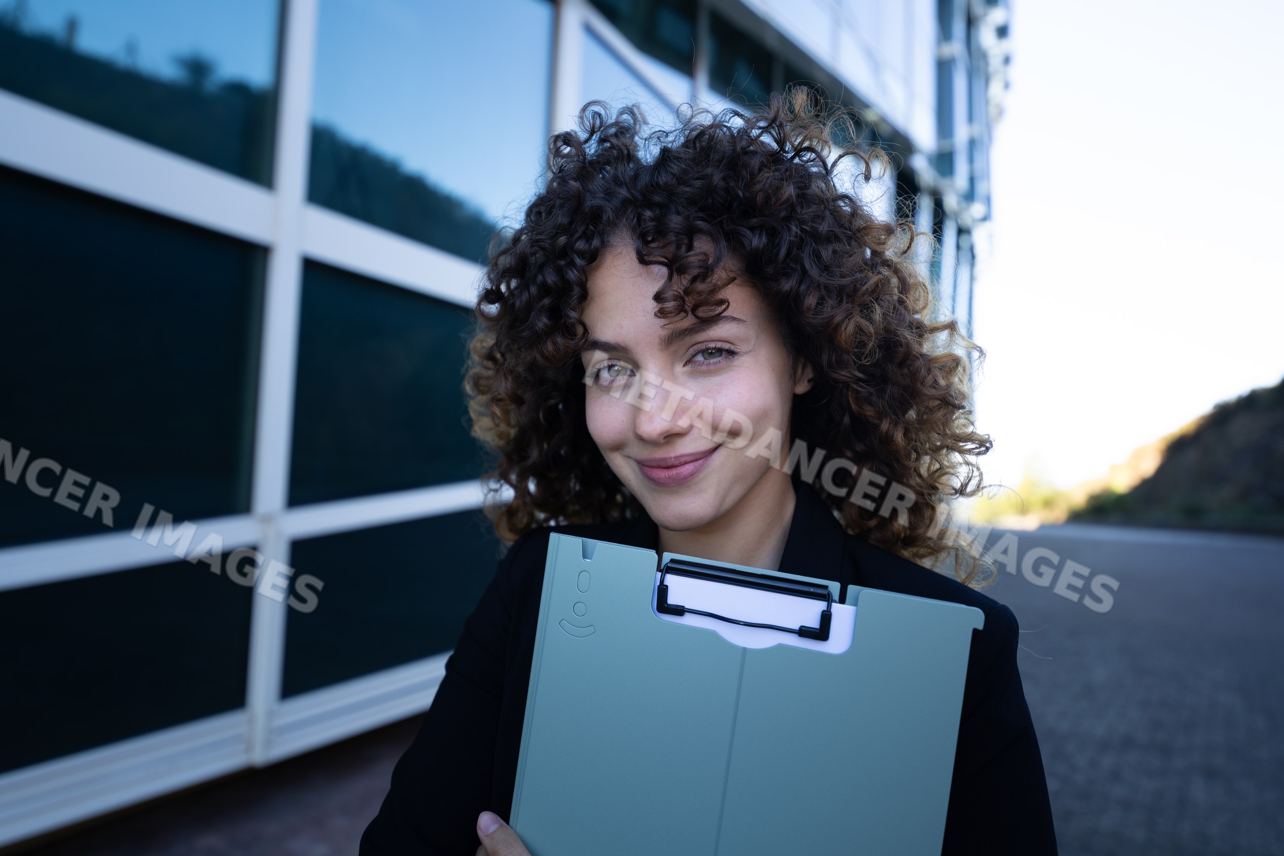 Businesswoman holding clipboard outdoors near modern building in Spain