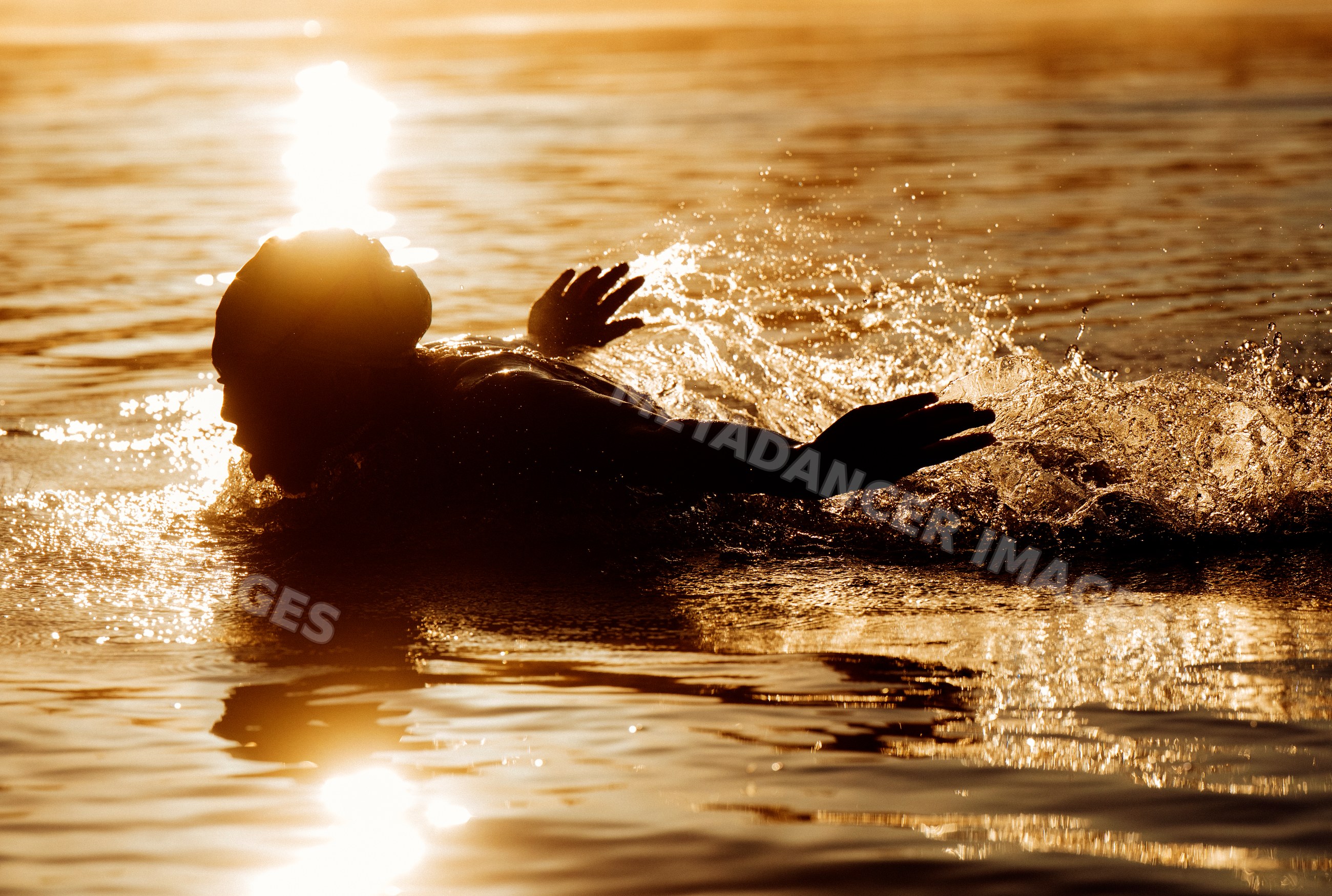 White swimmer splashing water during golden hour sunset