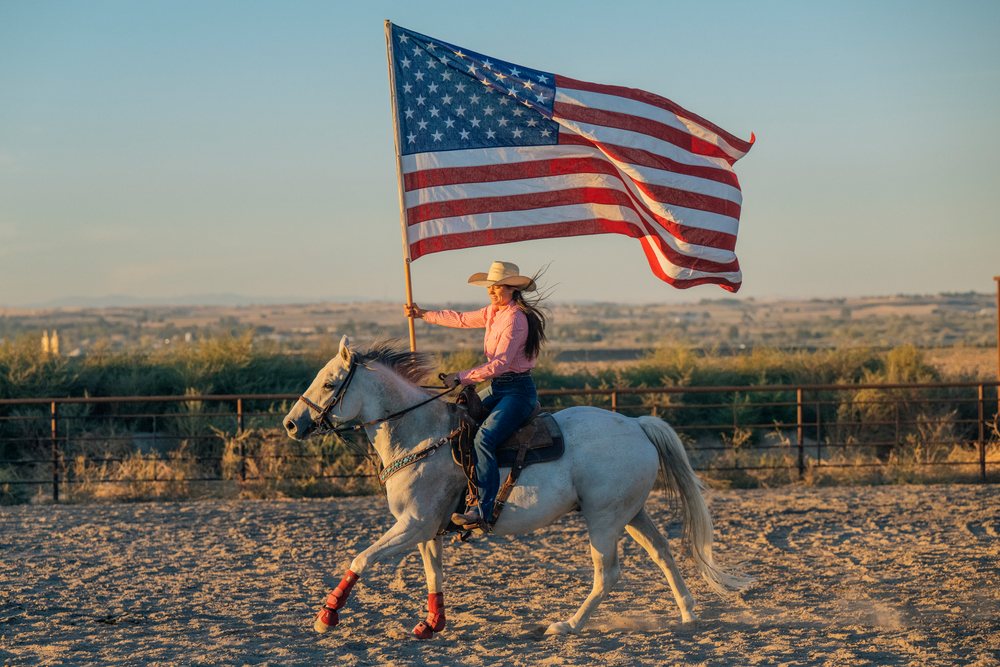 White woman riding horseback holding american flag