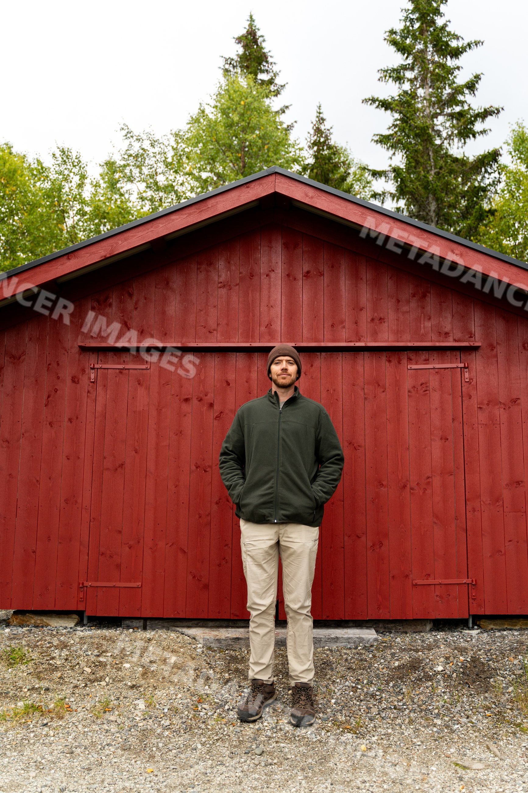 Man standing outside red wooden shed in Norway outdoors