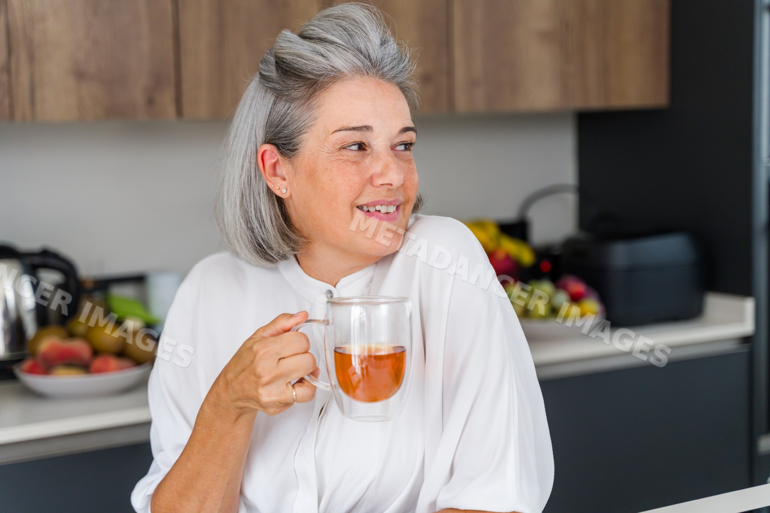 Middle-aged white woman enjoying tea in modern kitchen in Spain