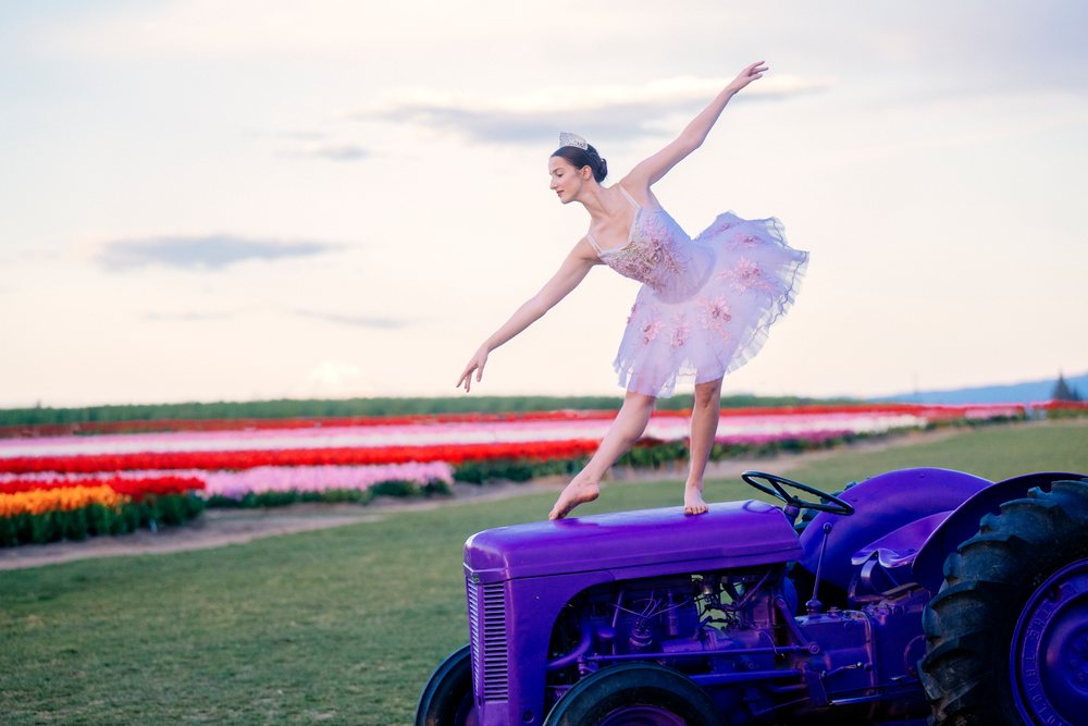 Ballet white dancer balancing gracefully on a purple tractor