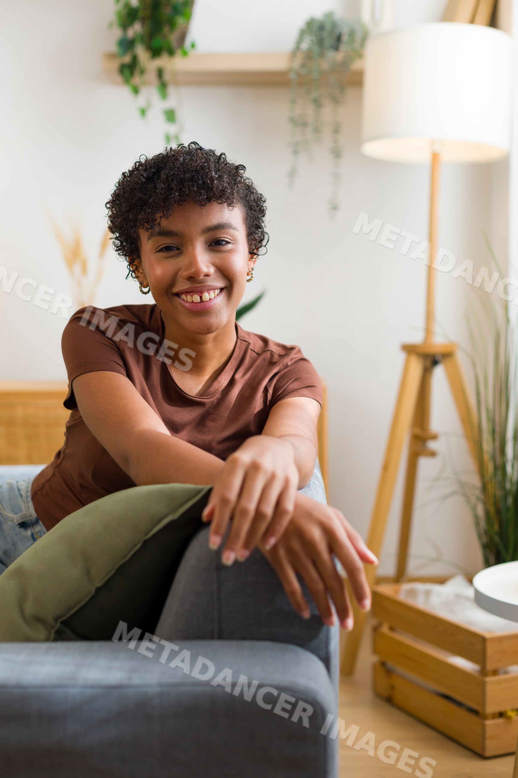 Young African American woman smiling on gray sofa in cozy living room