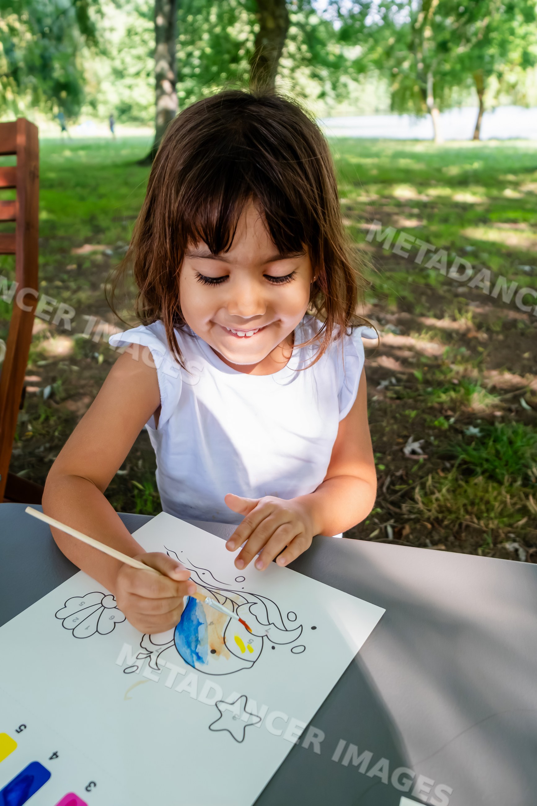 White child painting fish drawing with watercolors outdoors