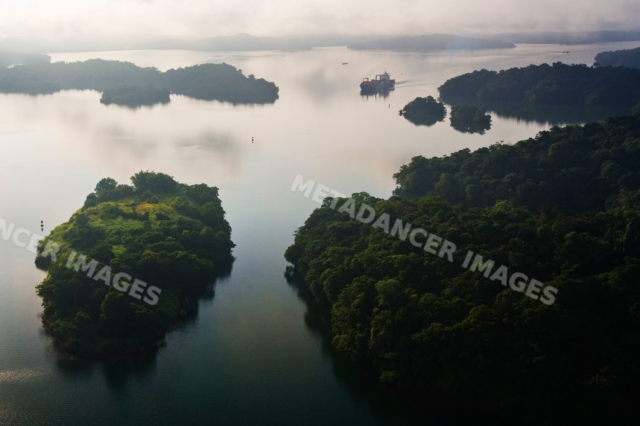 Container ship in lago gatun surrounded by tropical forest islands
