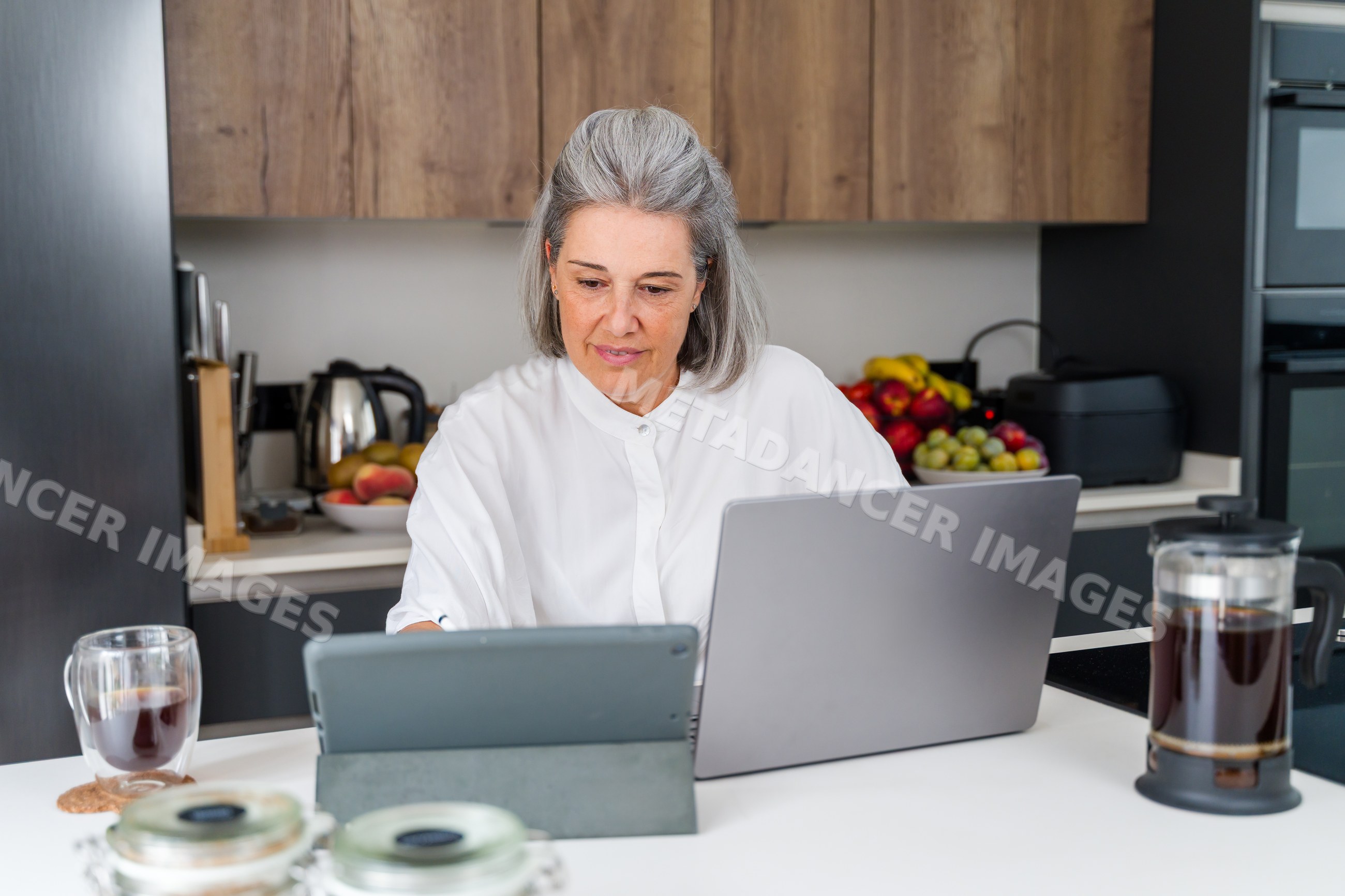 Mature white woman working with tablet and laptop