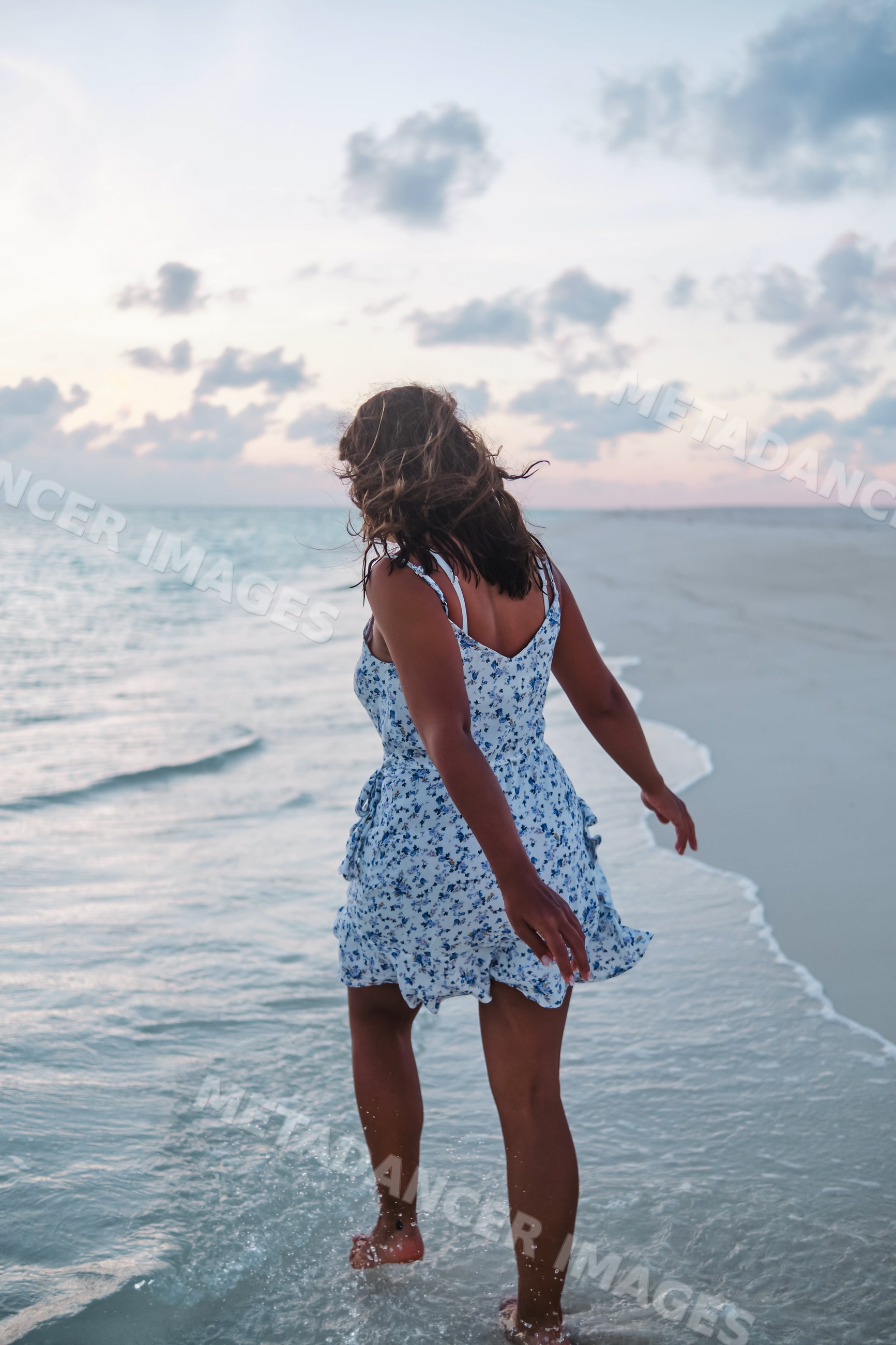 A white woman walking barefoot along the shoreline