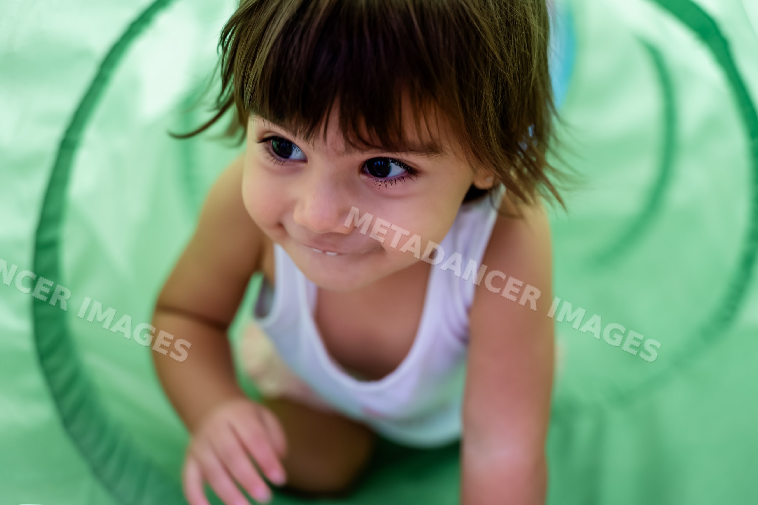 Baby crawling and smiling inside a green play tunnel
