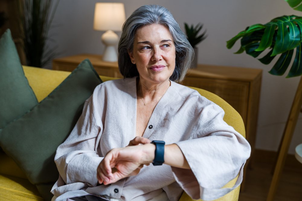 Mature white woman sitting on yellow sofa looking contemplatively