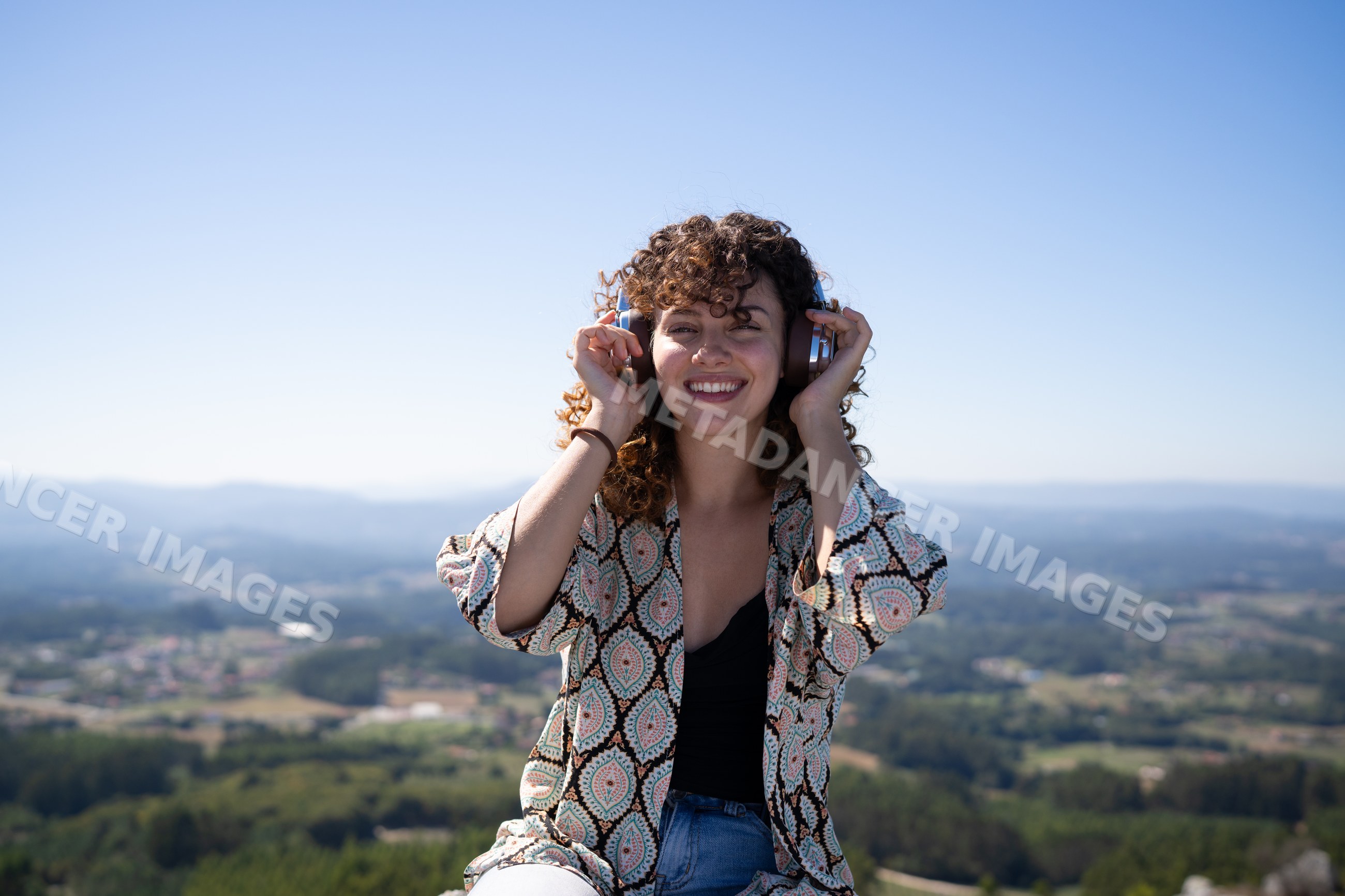 White woman listening to music with headphones outdoors at Pico Sacro