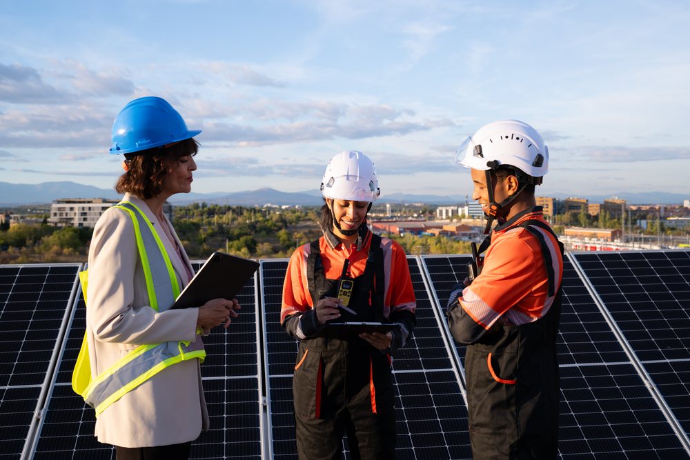 Engineers and Hispanic and white workers inspecting solar panels
