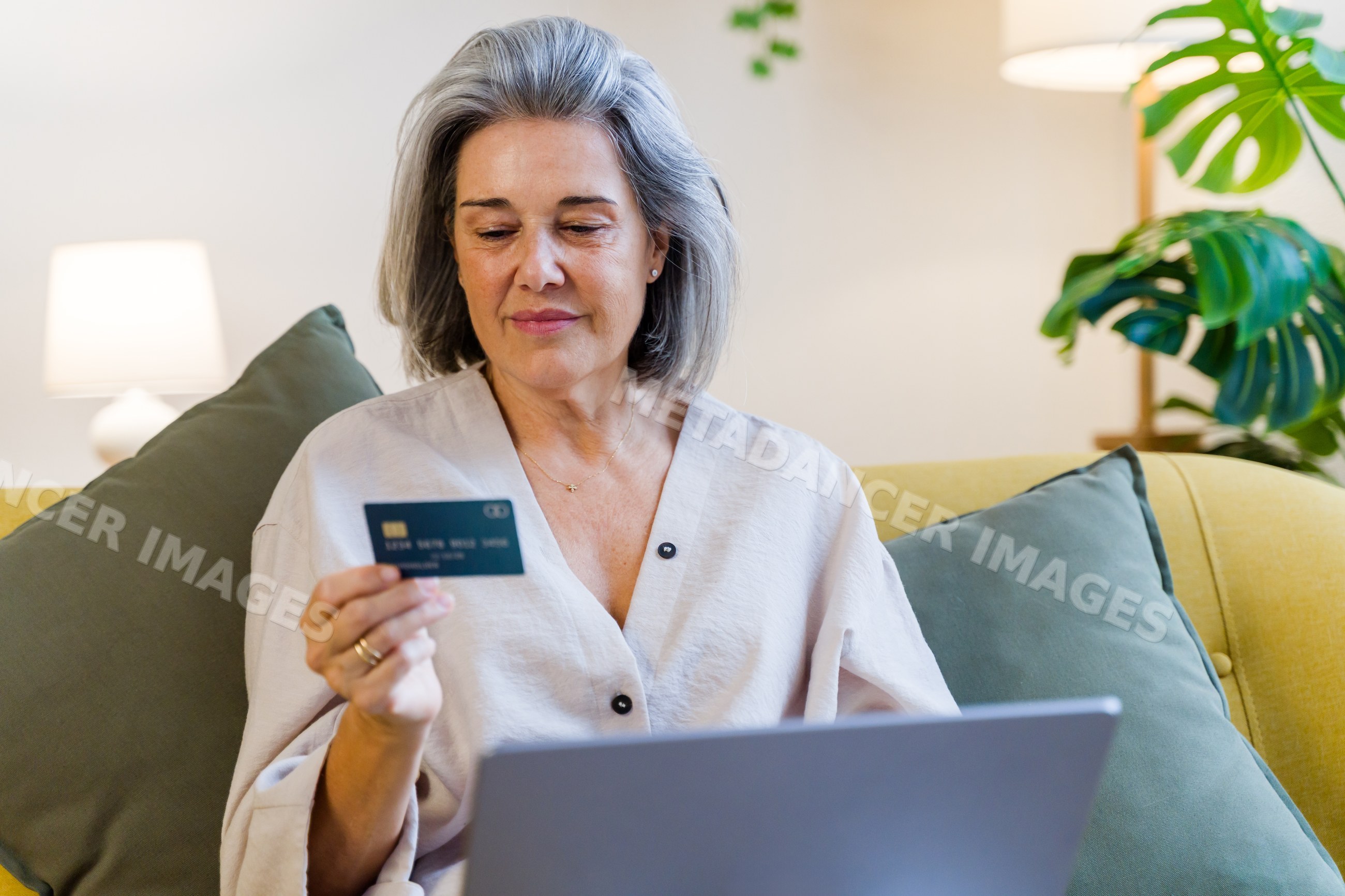Middle-aged white woman using credit card and laptop at home