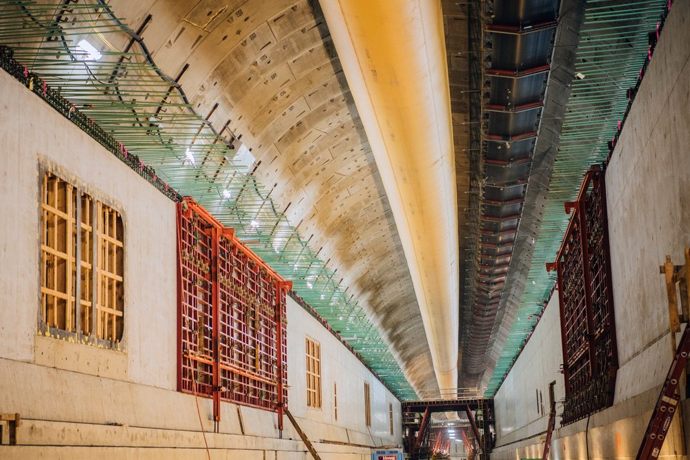 Interior view of a concrete tunnel under construction with overhead