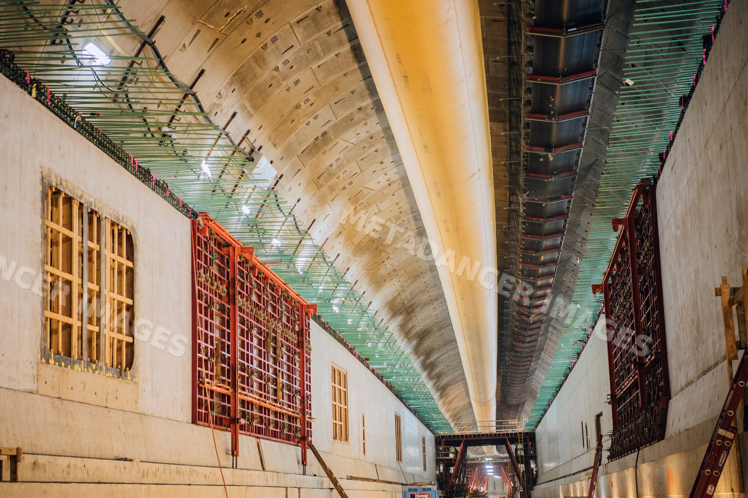 Interior view of a concrete tunnel under construction with overhead