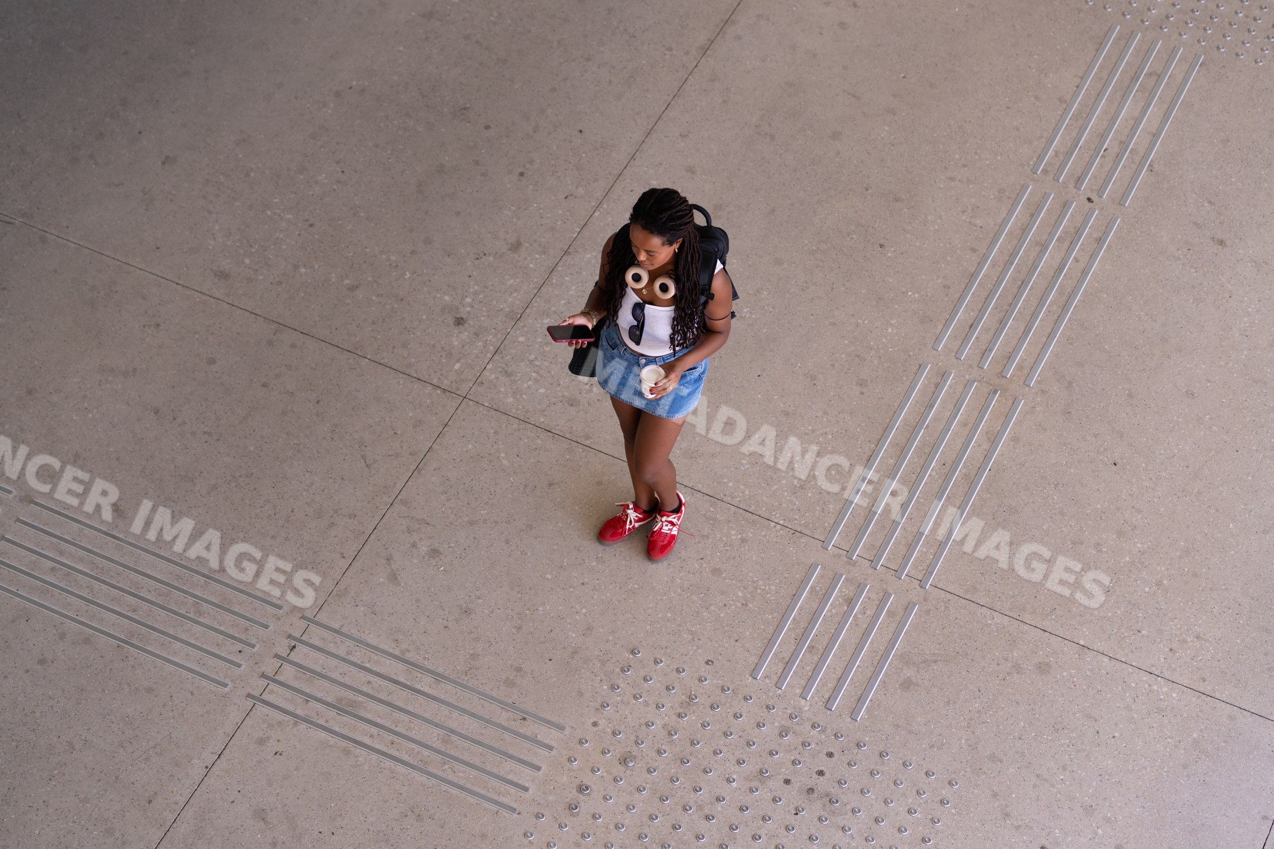 A African American woman standing on tactile pavement looking