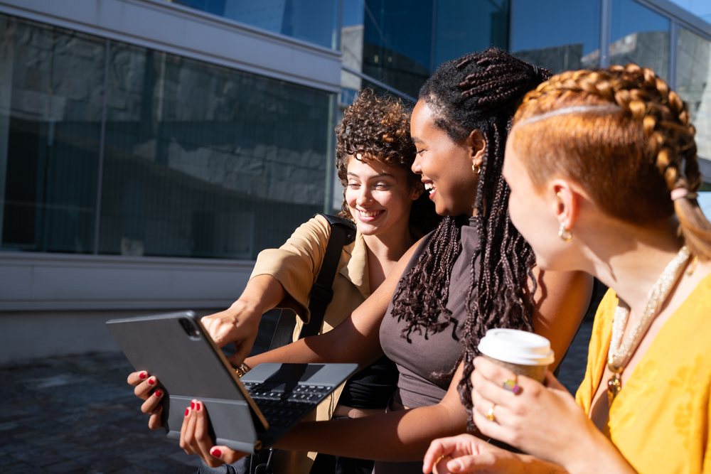 African American and white women sharing content on a tablet outdoors