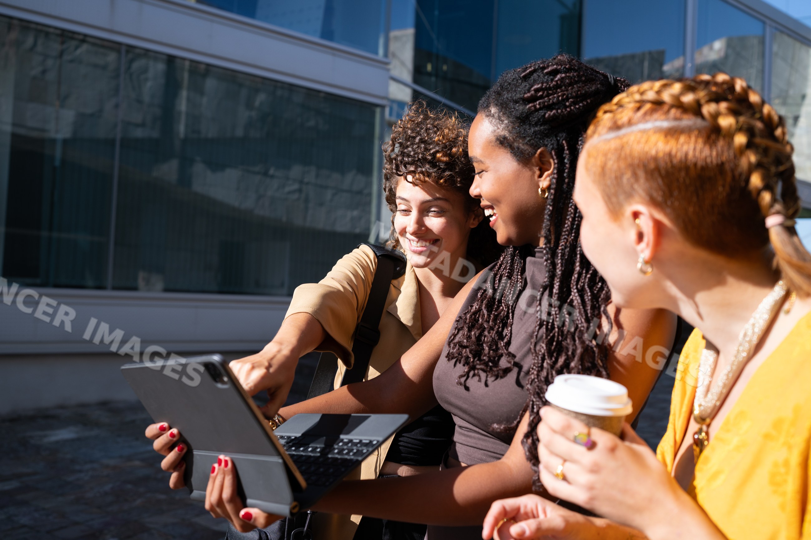 African American and white women sharing content on a tablet outdoors