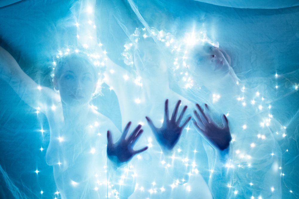 Three white women with glowing light garlands