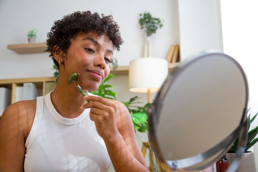 African American woman using jade facial roller during skincare