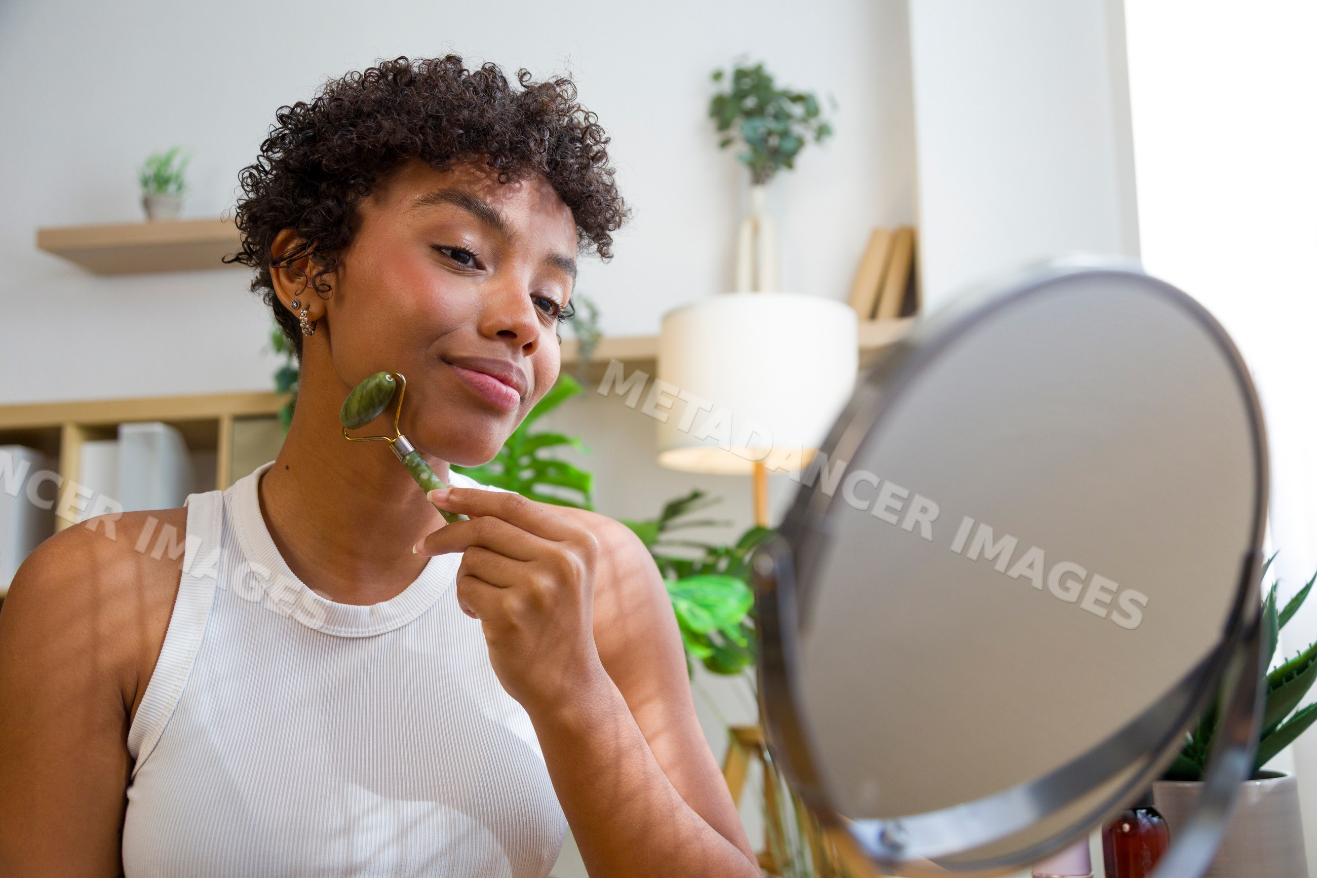 African American woman using jade facial roller during skincare