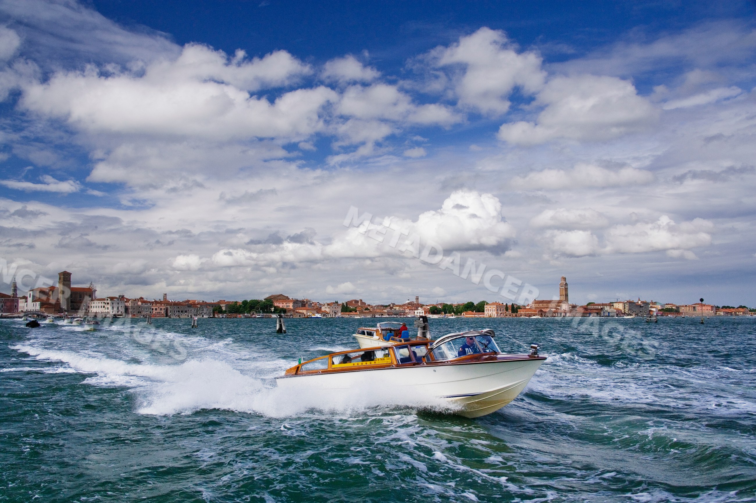 Water taxi cruising on venice lagoon with cityscape background
