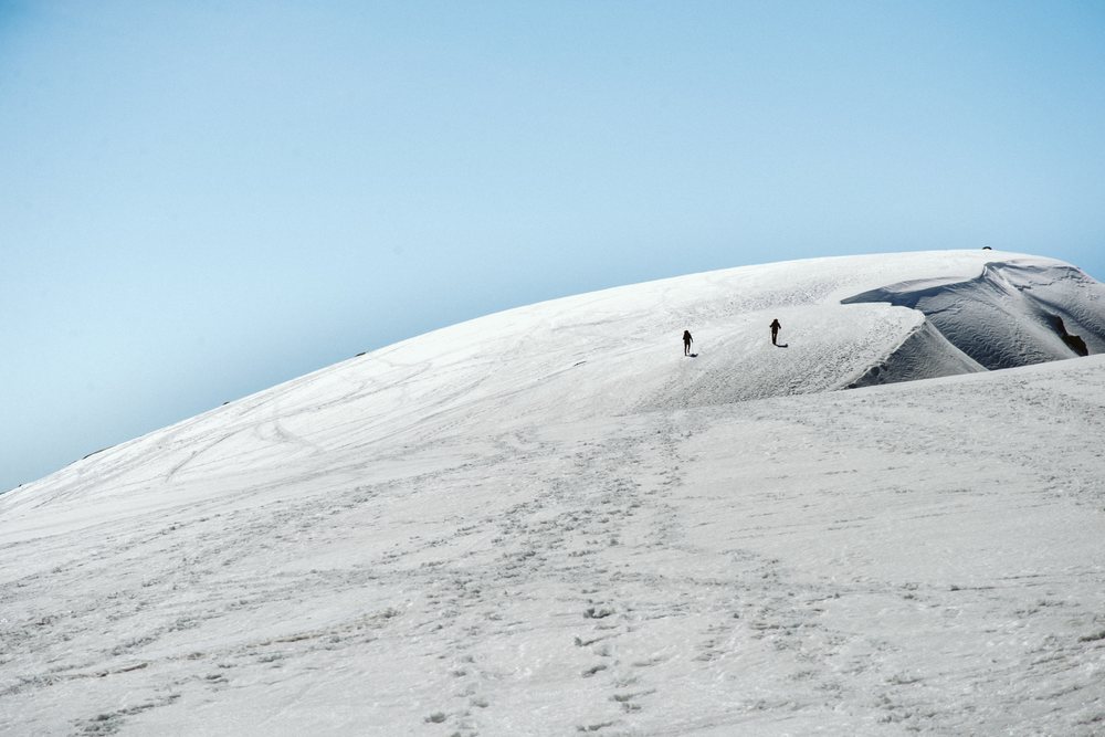 Climbers ascending snowy mountain hill in Spain landscape