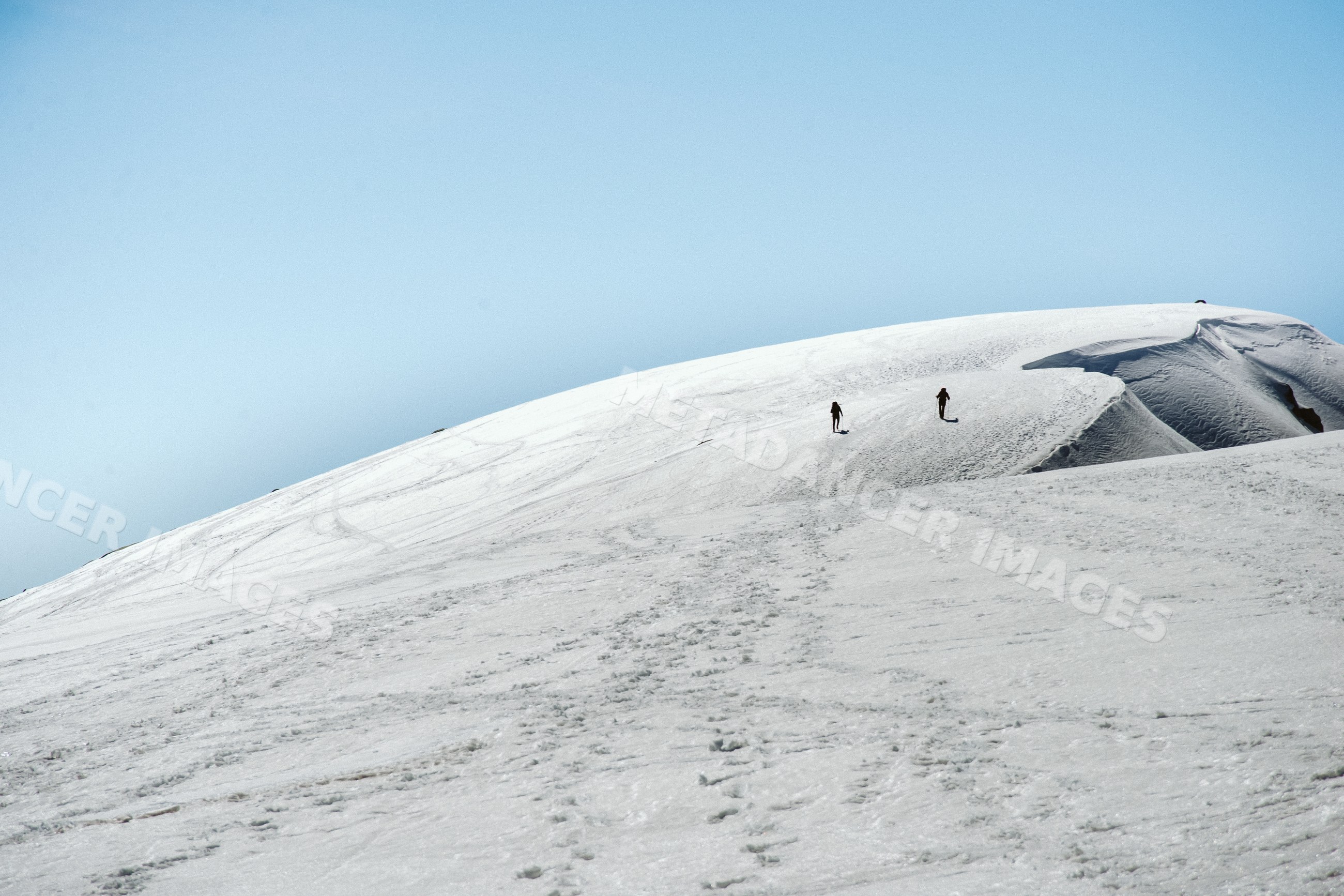 Climbers ascending snowy mountain hill in Spain landscape