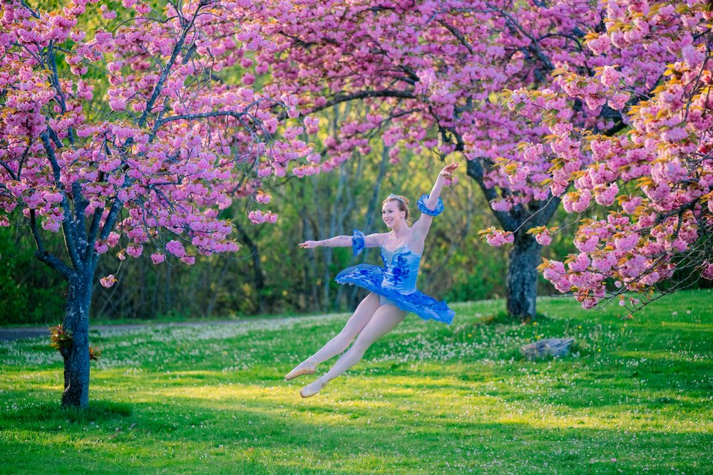 Ballet dancer performing jump under pink