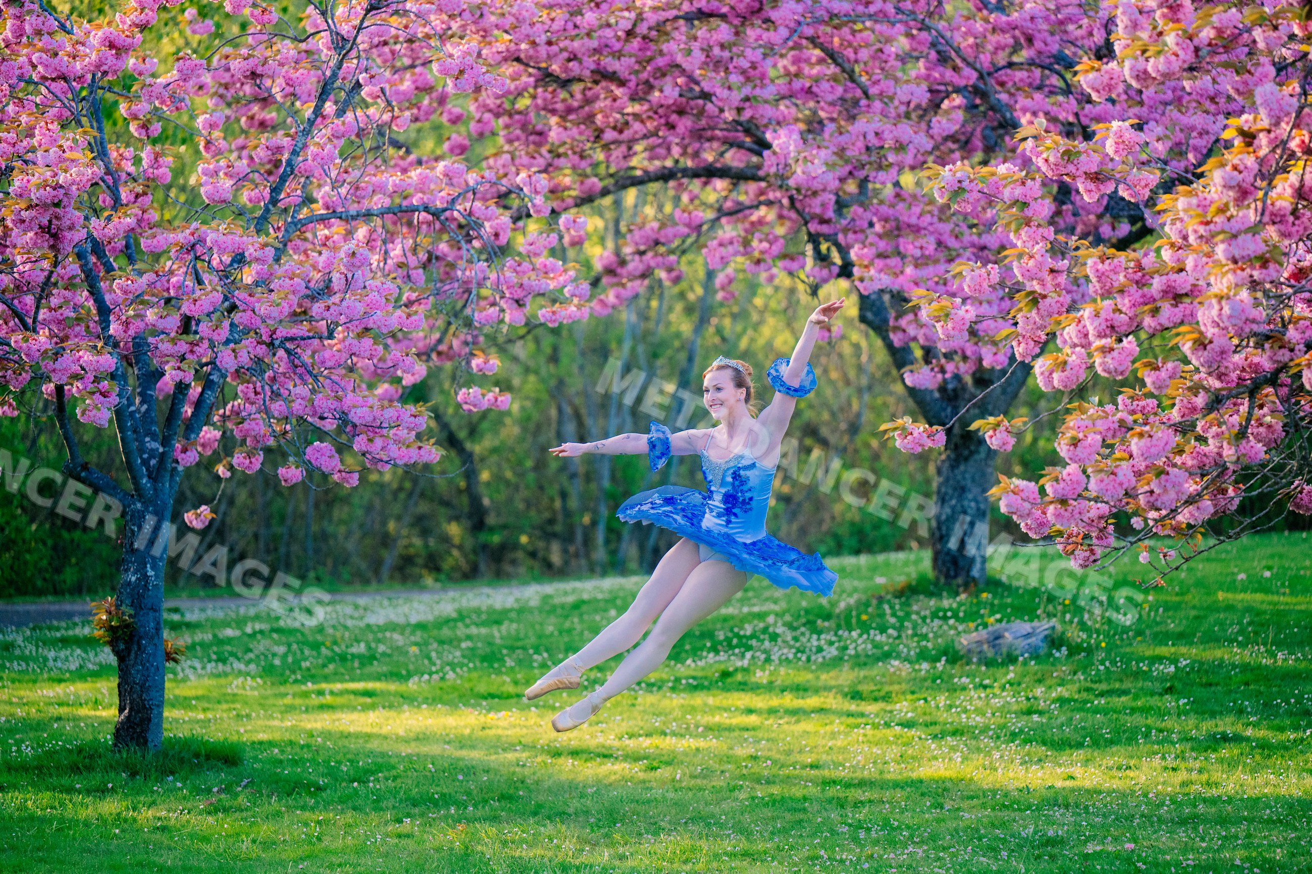 Ballet dancer performing jump under pink