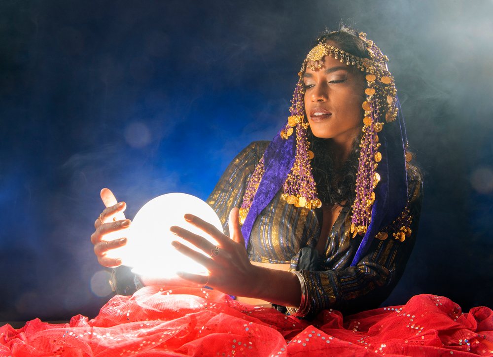 A South Asian woman dressed as a mystical figure holds a glowing