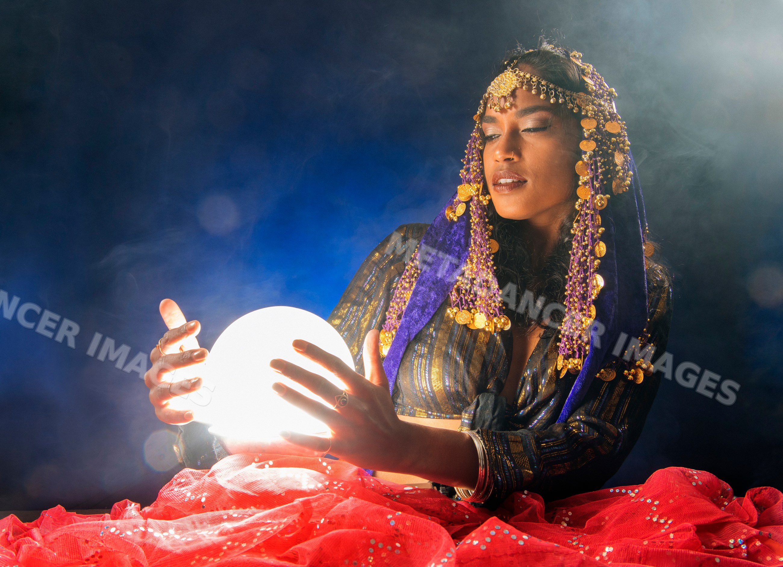 A South Asian woman dressed as a mystical figure holds a glowing