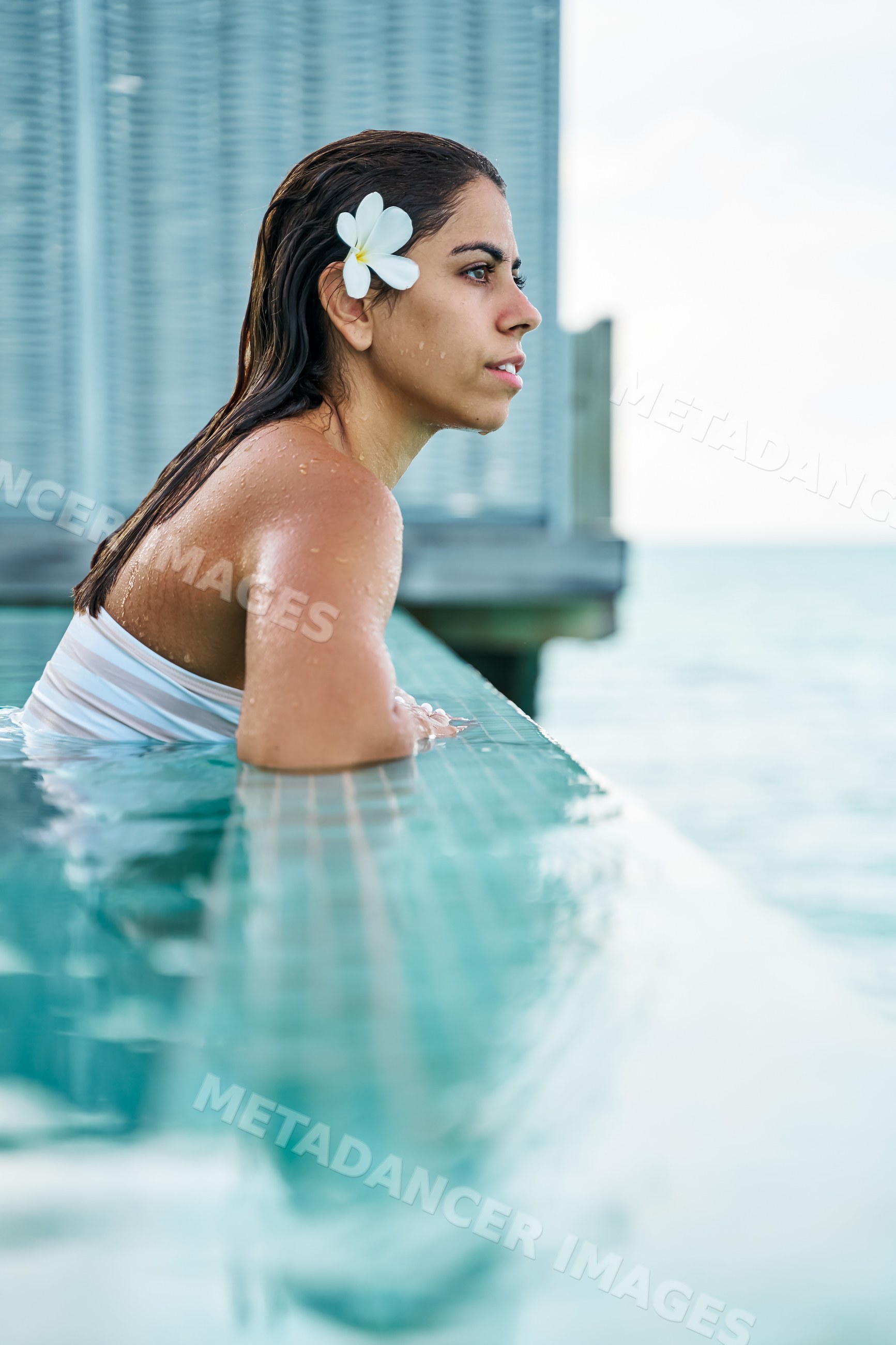 A white woman relaxes in a swimming pool overlooking the ocean