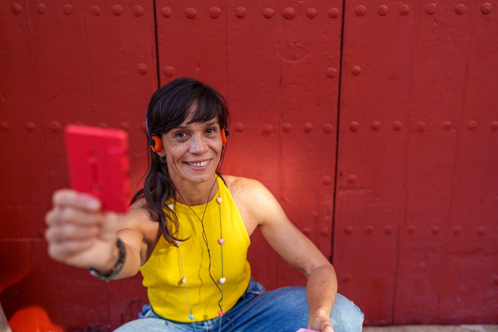Hispanic woman smiling with red cassette tape in front of red door