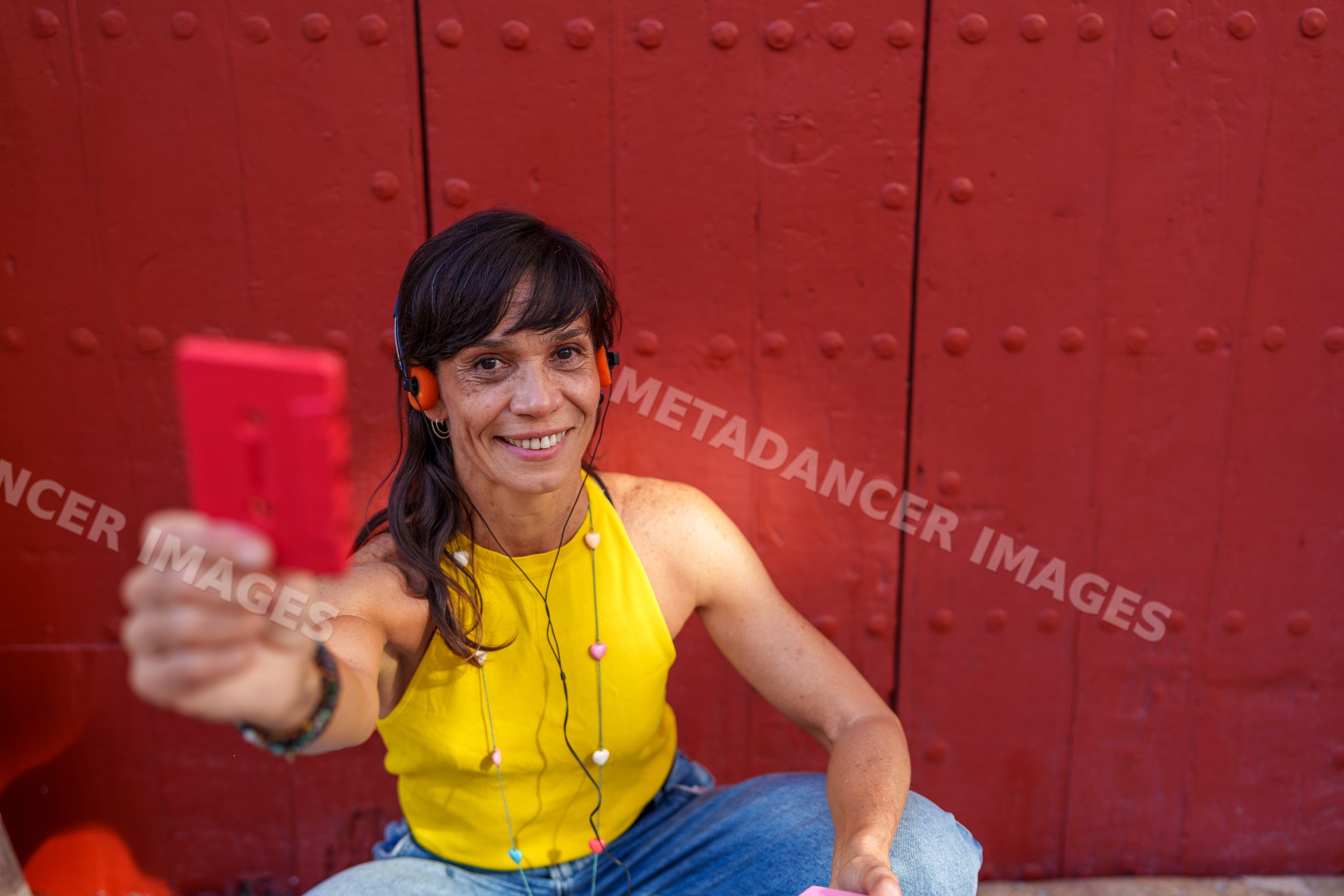 Hispanic woman smiling with red cassette tape in front of red door