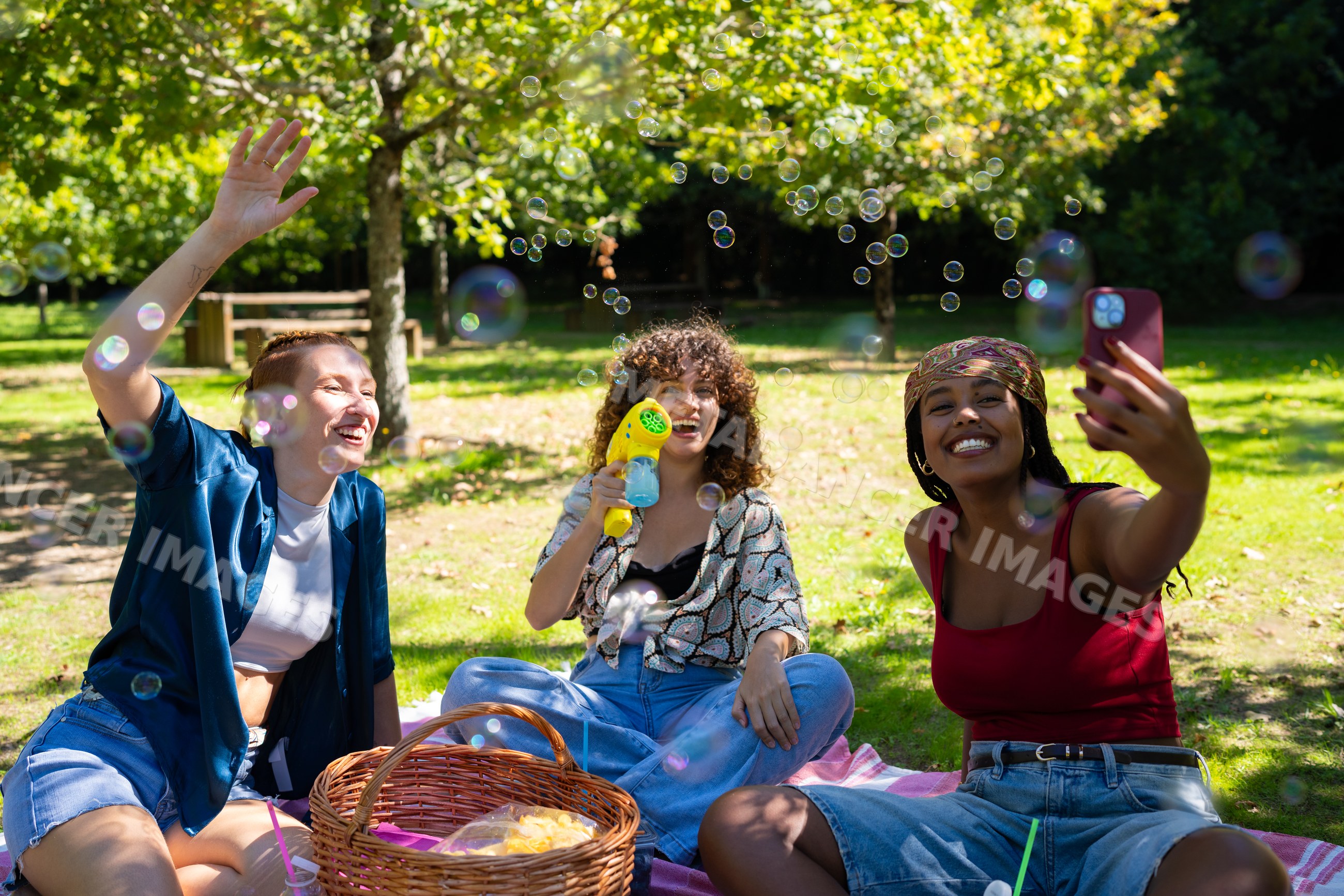 Friends playing with bubbles during a sunny picnic in a park in Spain