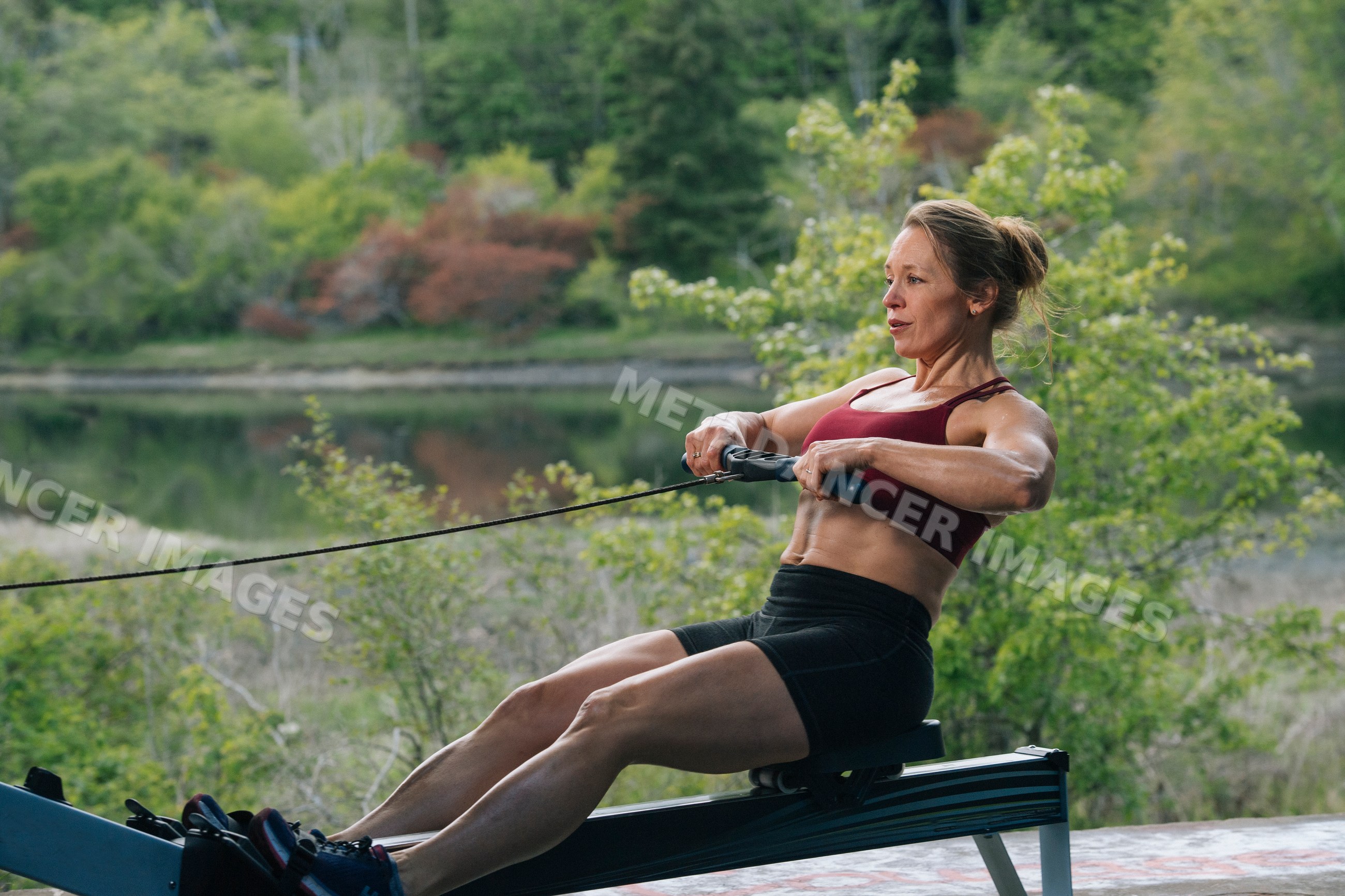 White woman exercising on rowing machine outdoors near lake