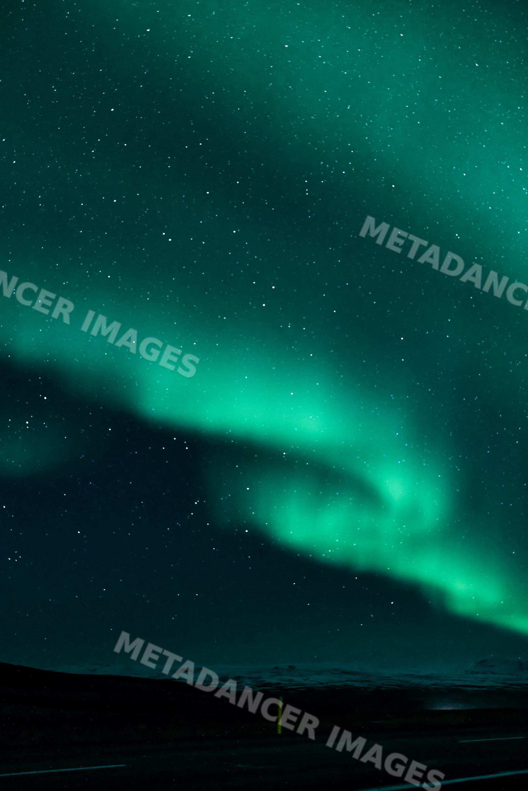 The northern lights glow vividly over a dark night sky