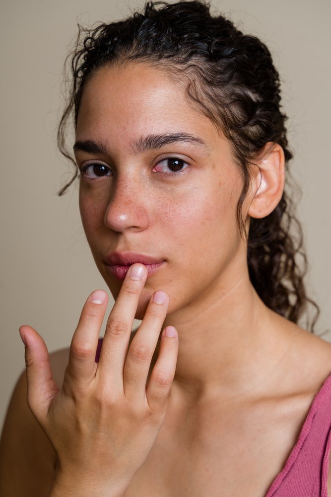 Hispanic woman touching lips in close-up studio portrait in a studio