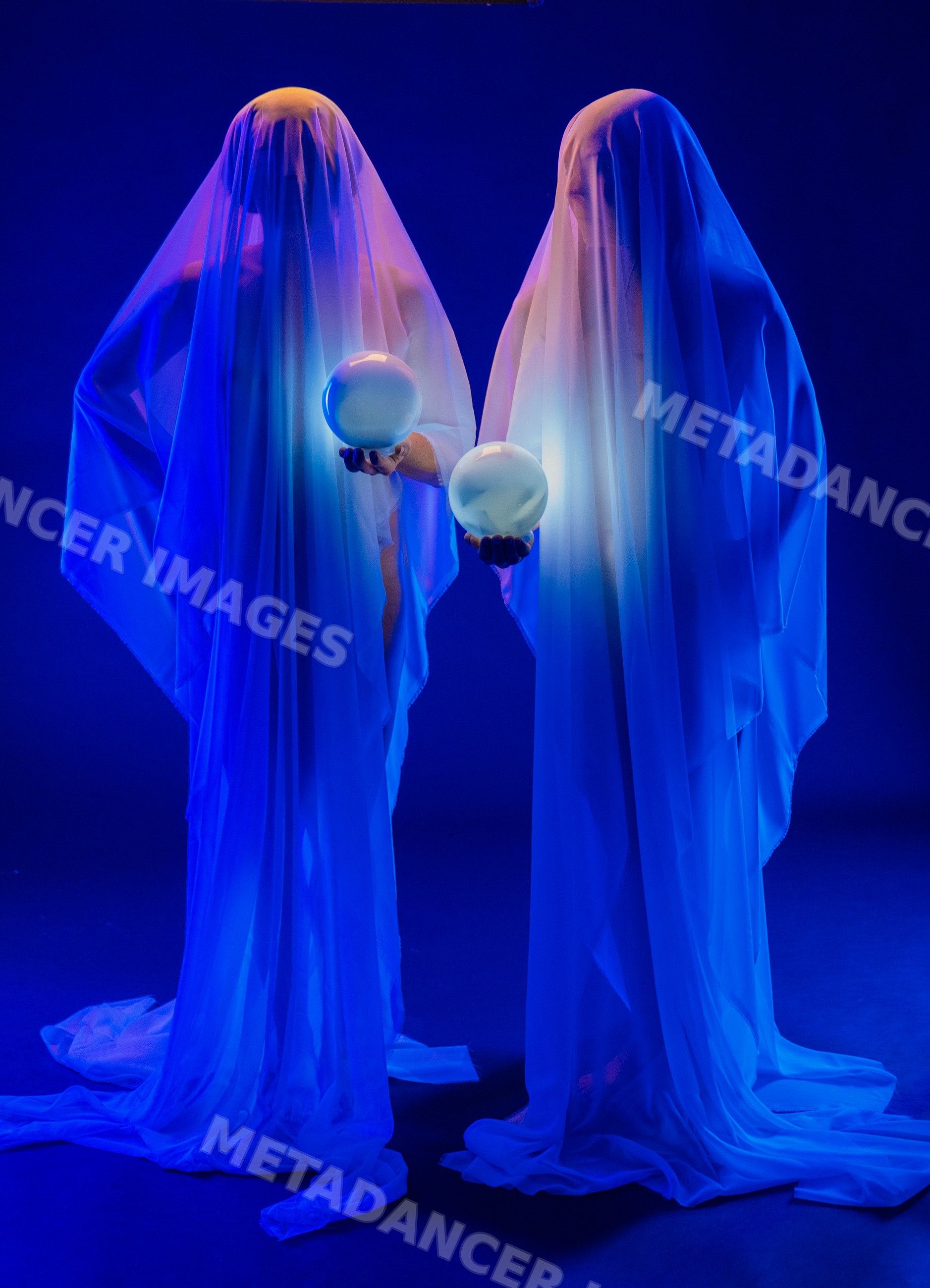 Two ghostly figures holding glowing spheres in blue-lit studio