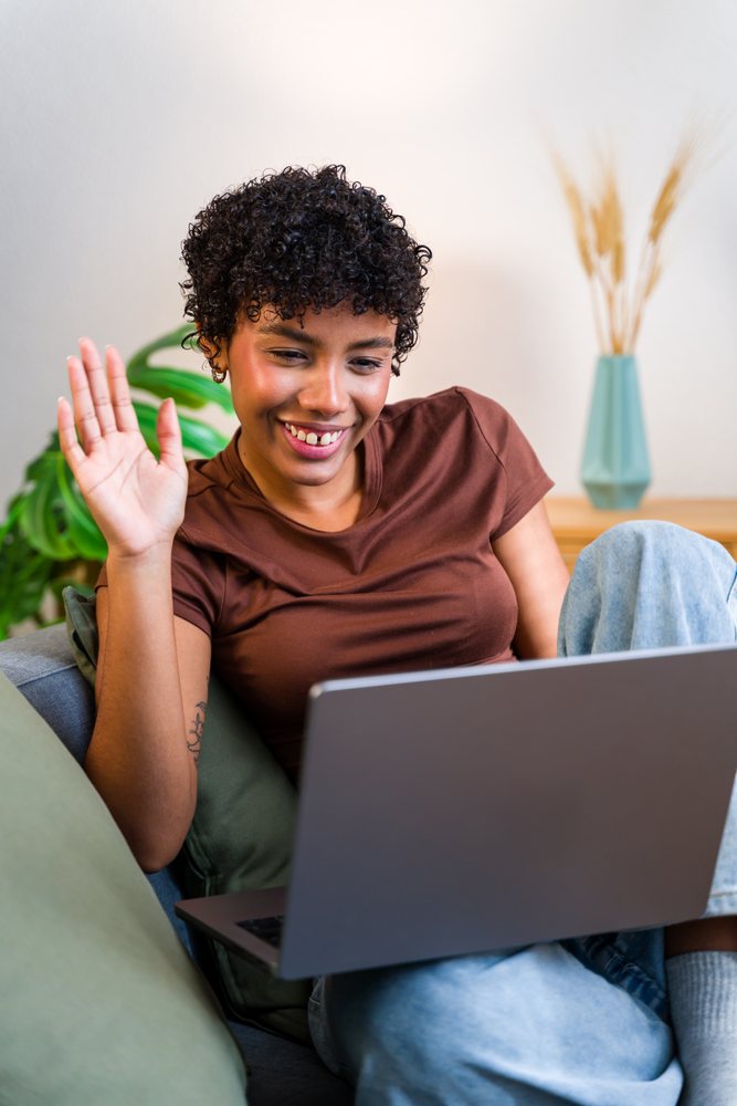 African American woman using laptop and waving during video call