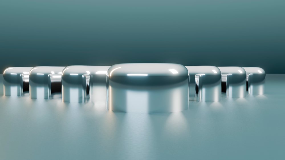 Abstract line of metallic capsules on a reflective surface